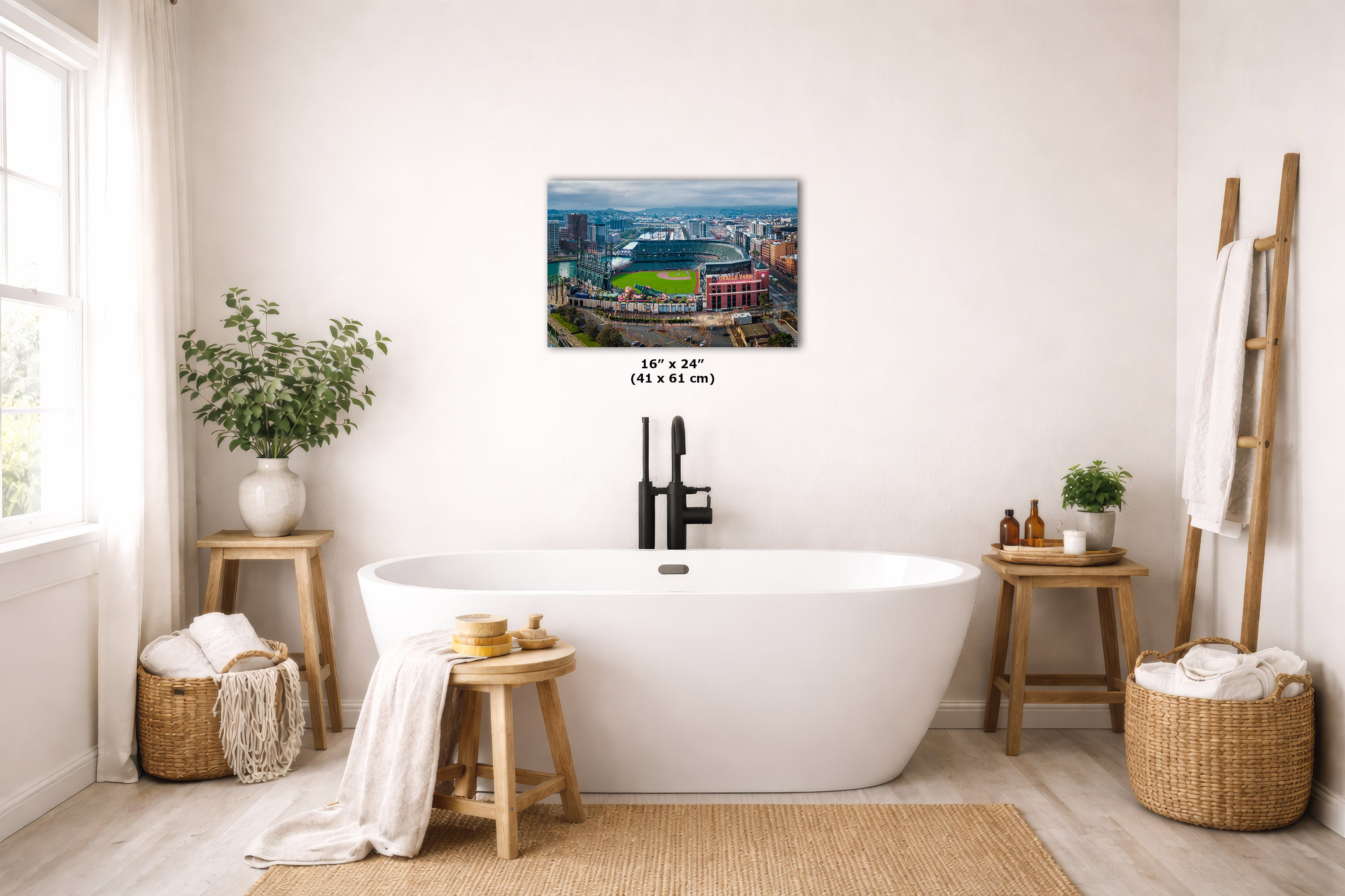 A freestanding white bathtub in a bright, neutral-toned bathroom with a San Francisco skyline print above it. The scene includes wooden stools, woven baskets, plants, and a ladder-style towel rack.