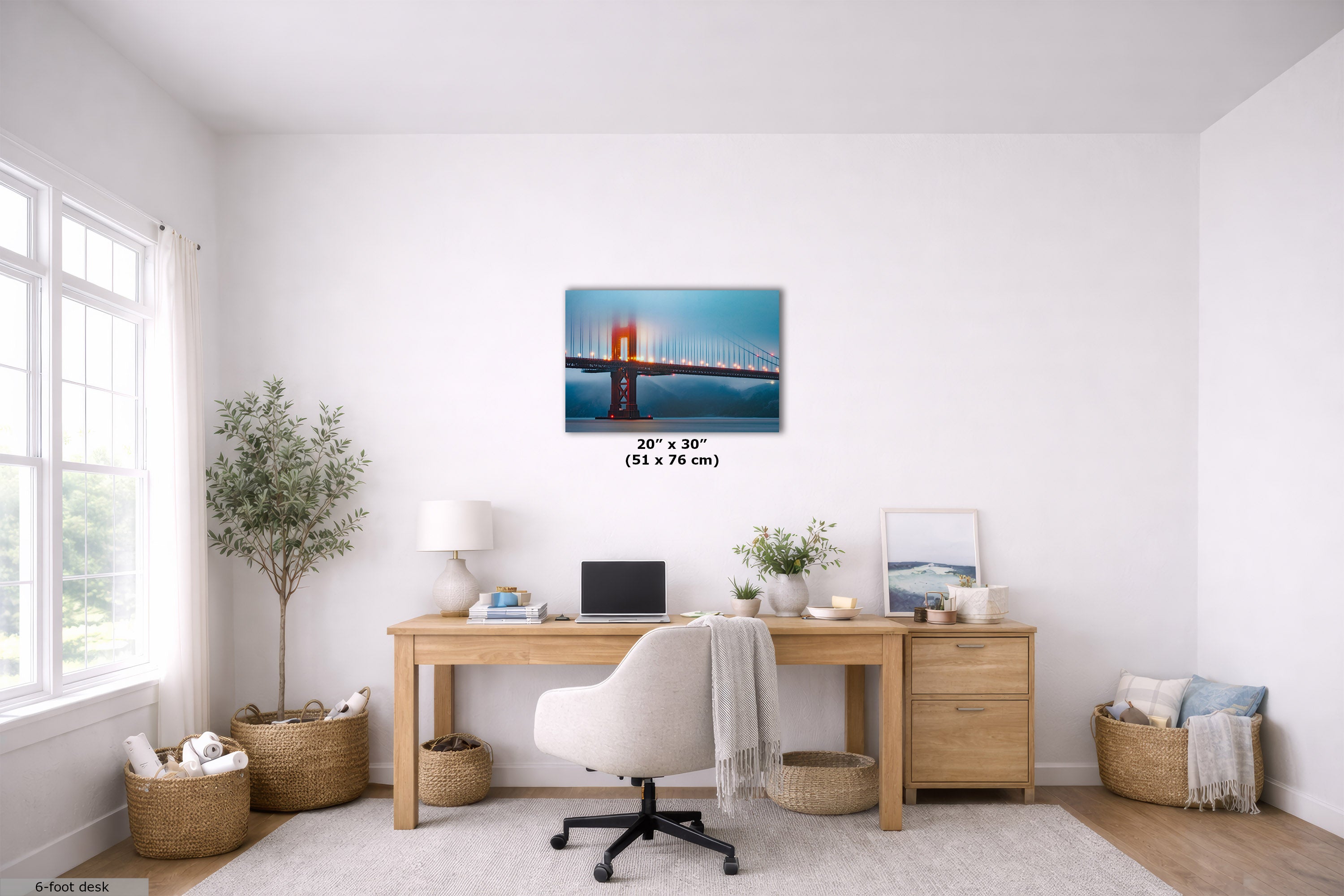 A 20x30 inch canvas print of the Golden Gate Bridge is displayed on a white wall in a bright, modern home office setting with a wooden desk, white chair, and plants.