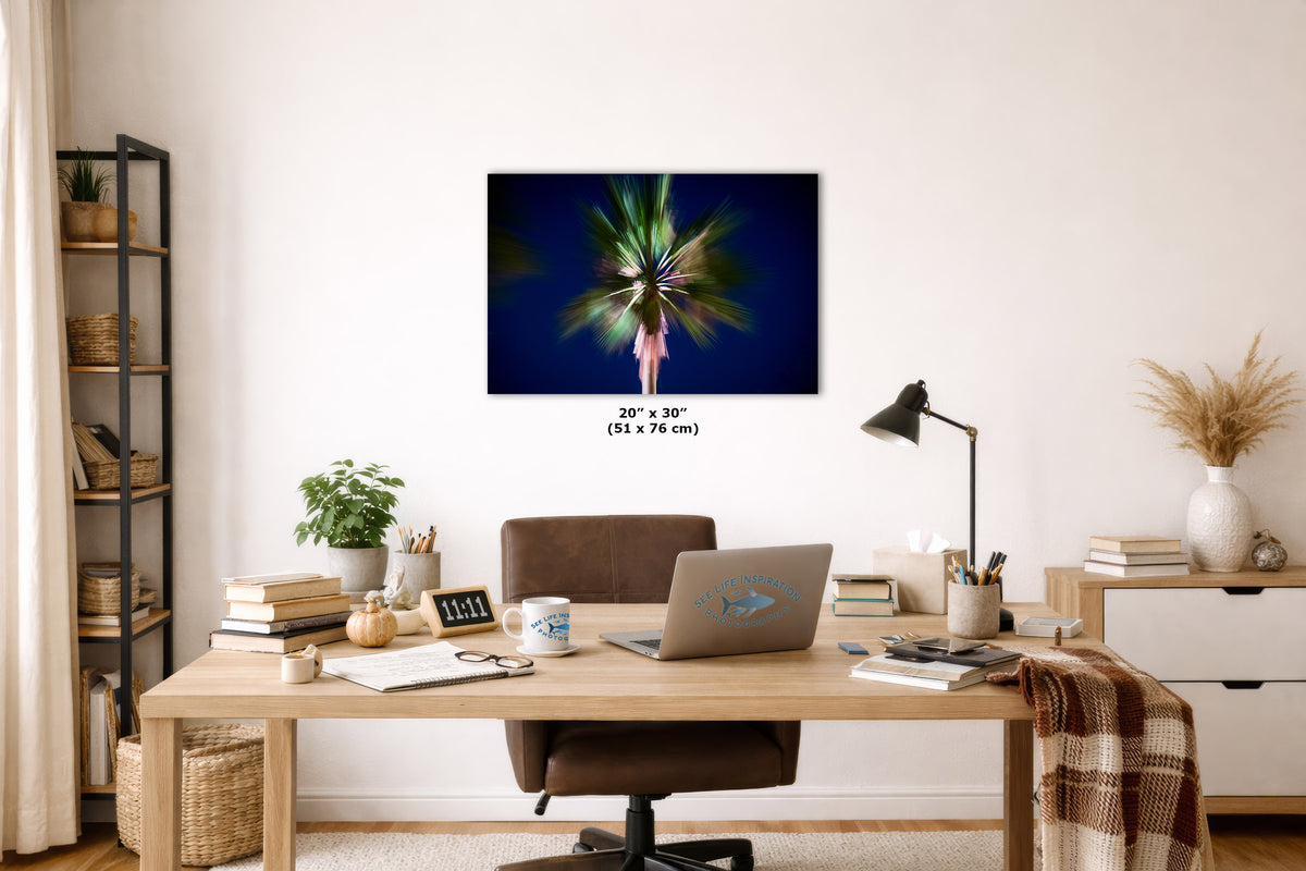 A wall art print showing a colorful, abstract tropical or palm tree scene on a dark background, displayed above a wooden desk in a styled home office setting. The print includes size text indicating 20 x 30 inches.