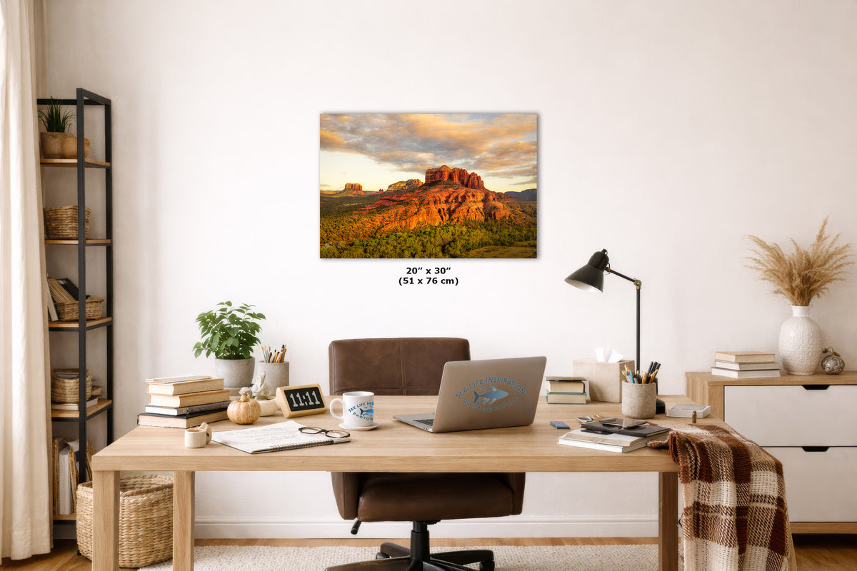 Home office with a desk, laptop, and decorative items, featuring a large wall art print of a desert landscape.