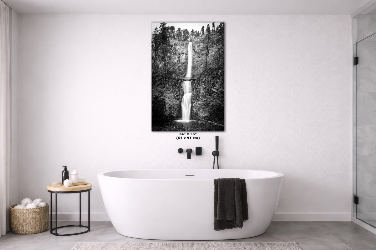 A black and white waterfall wall art print displayed above a freestanding white bathtub in a modern bathroom setting.