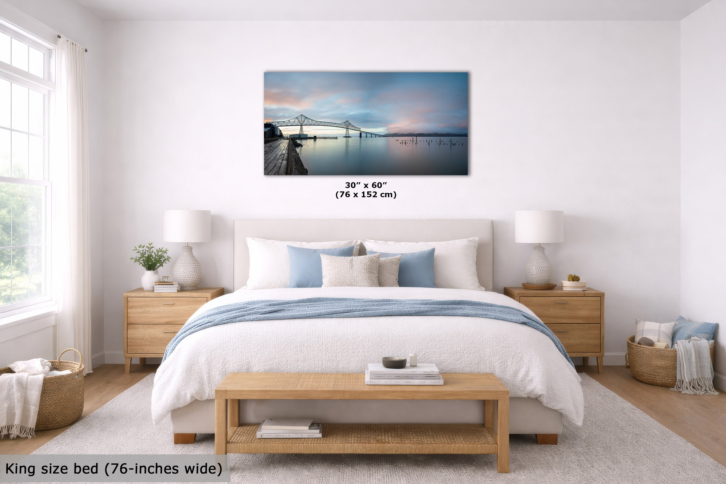 A framed wall art print showing a pier and bridge over calm water, displayed above a neatly made bed in a bright, modern bedroom. The print is labeled 30 x 60 inches (76 x 152 cm), and the room scene includes a bed, nightstands, lamps, and a bench.
