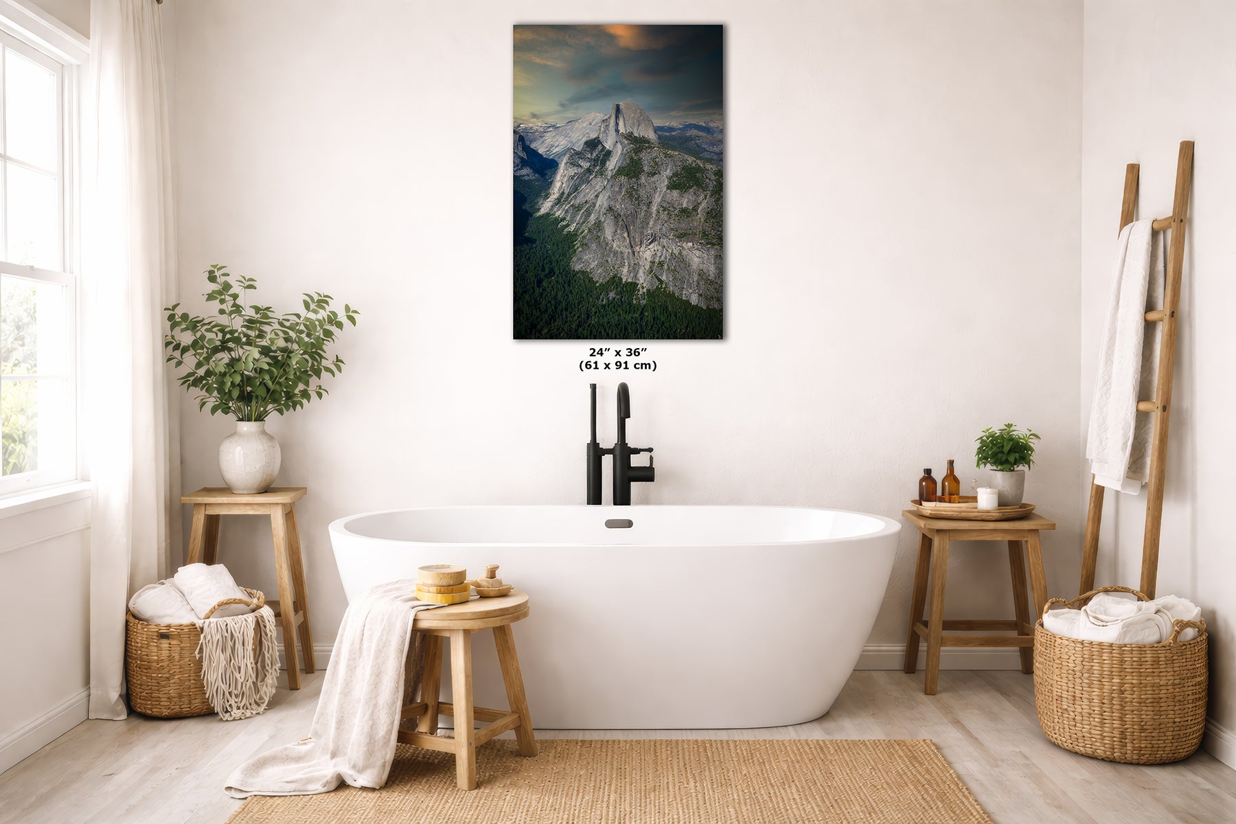 A vertical wall art print of Half Dome in Yosemite depicting a dramatic mountain landscape with a glowing sunset, styled in a bright, modern bathroom above a white freestanding bathtub.