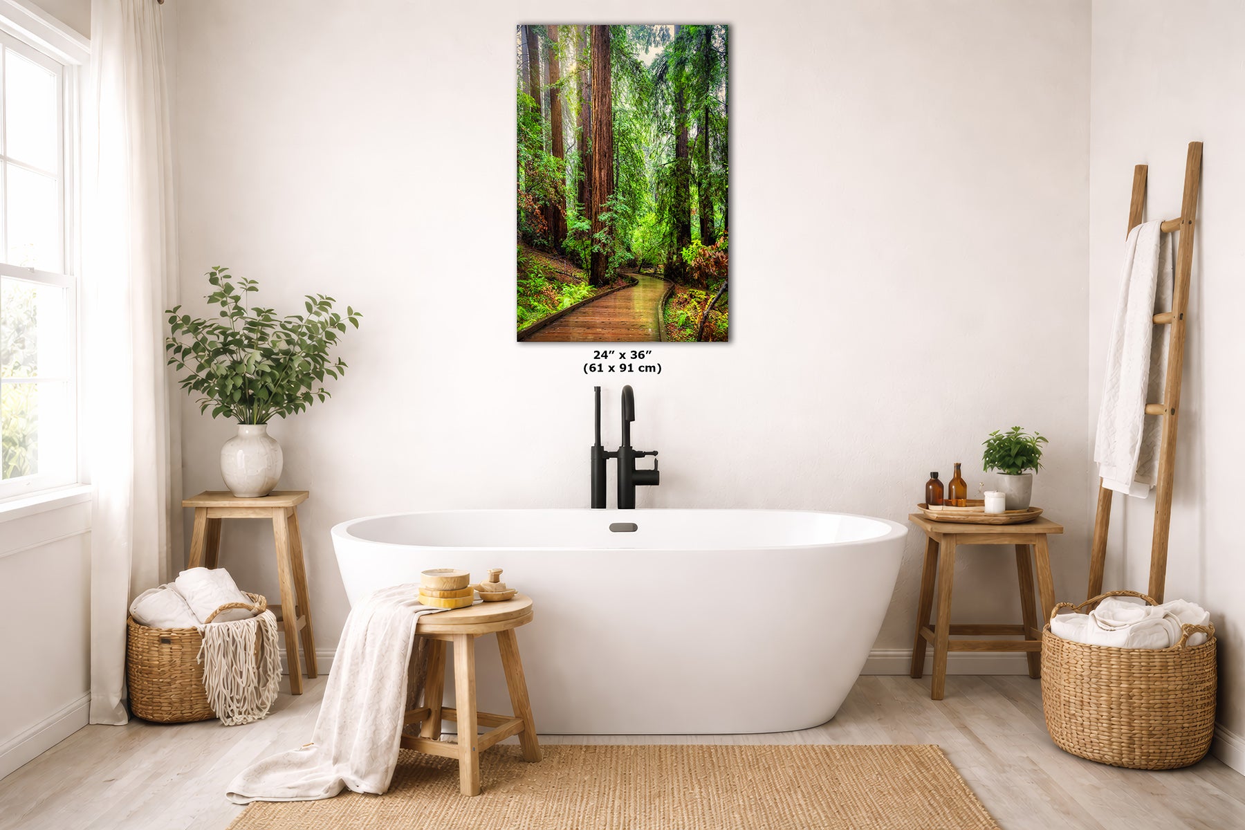 A vertical canvas wall art print depicting a lush green Redwood forest path, styled in a bright, modern bathroom above a white freestanding bathtub. The print features a wooden path winding through dense green trees under soft light, with dimensions '24" x 36"' printed on the frame.