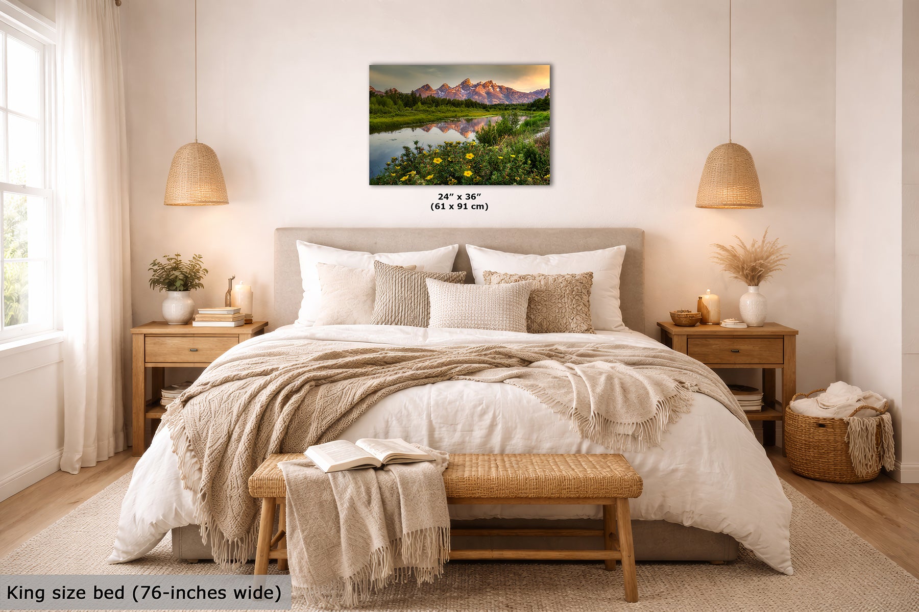A framed landscape wall art print showing the Grand Teton Mountains, a river, and wildflowers, displayed above a neatly made bed in a bright, modern bedroom. Small text below the artwork reads 24 x 36 inches, and text at the bottom left says King size bed (76-inches wide).