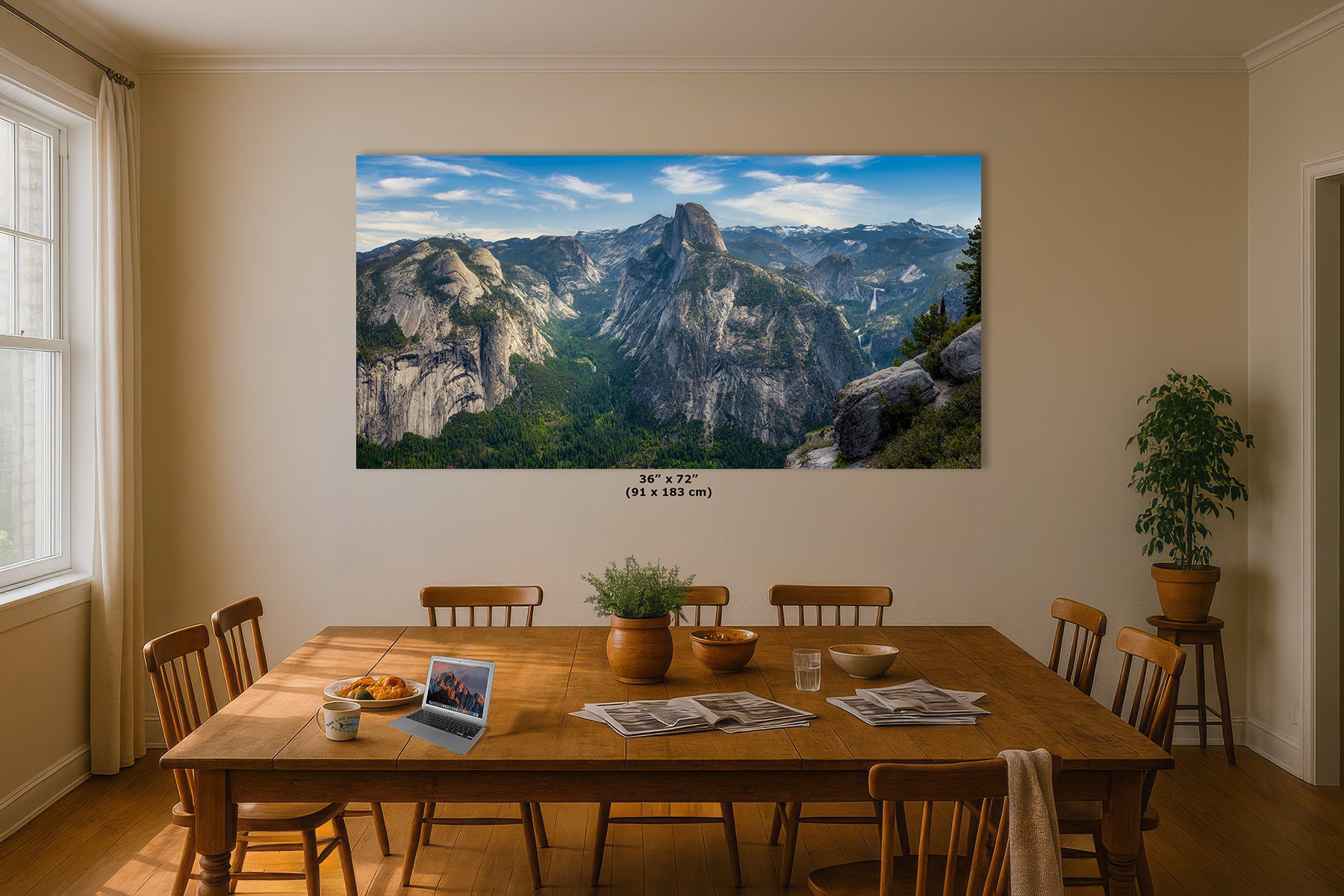 A large landscape wall art print showing Yosemite Valley with rocky cliffs of Half Dome and a blue sky, displayed above a wooden dining table in a real room. The print includes size text reading 36 x 72 in (91 x 183 cm) below it.