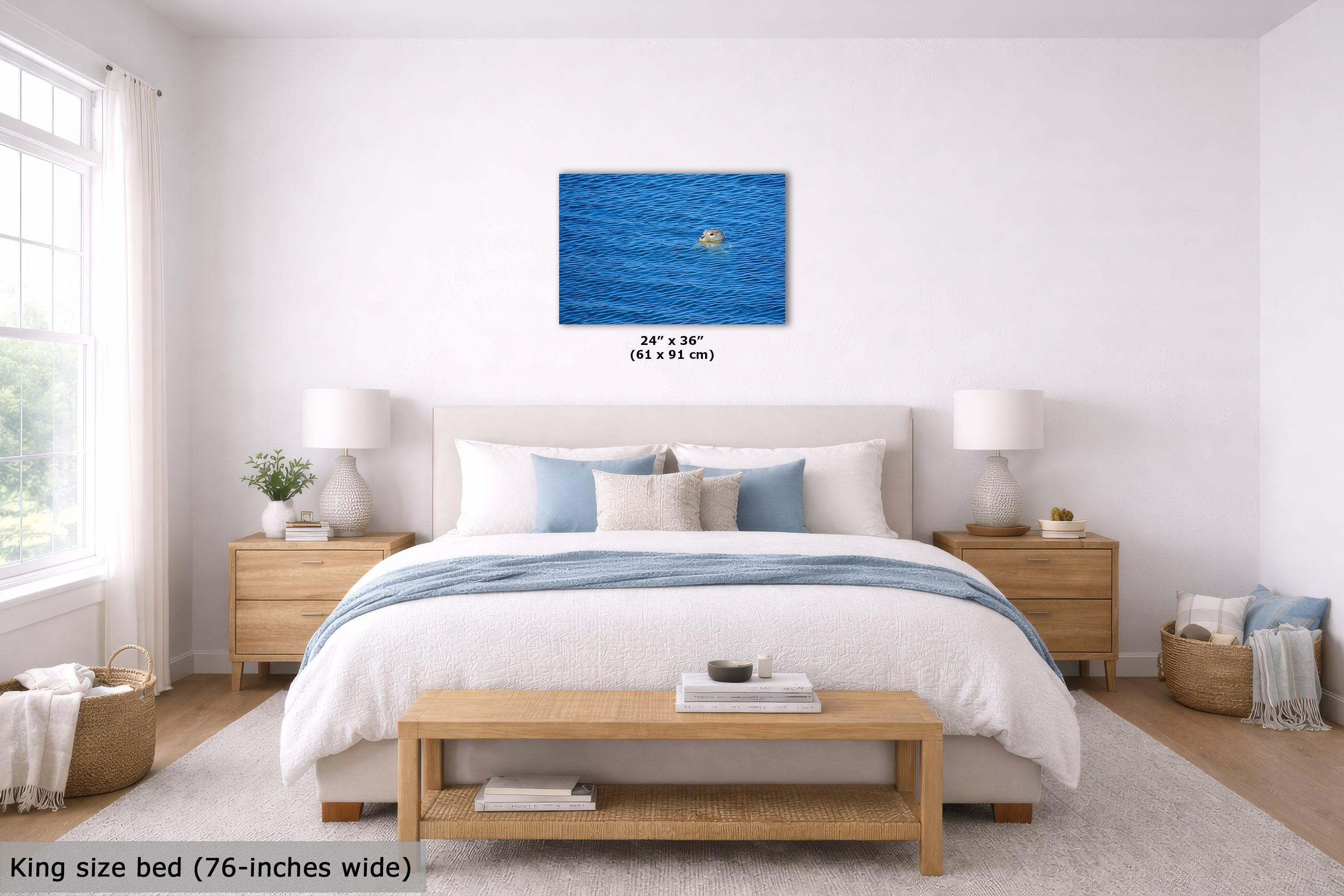 A bedroom mockup showing a blue ocean wall art print centered above a king-size bed. The print includes a small grey seal and has size text '24" x 36" (61 x 91 cm)' below it.