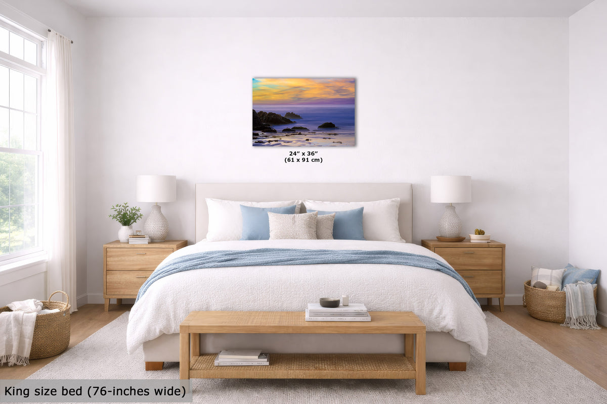 A wall art print showing a coastal sunset over the ocean, displayed above a neatly made bed in a bright, modern bedroom. The print includes a small size label reading 24" x 36" (61 x 91 cm).