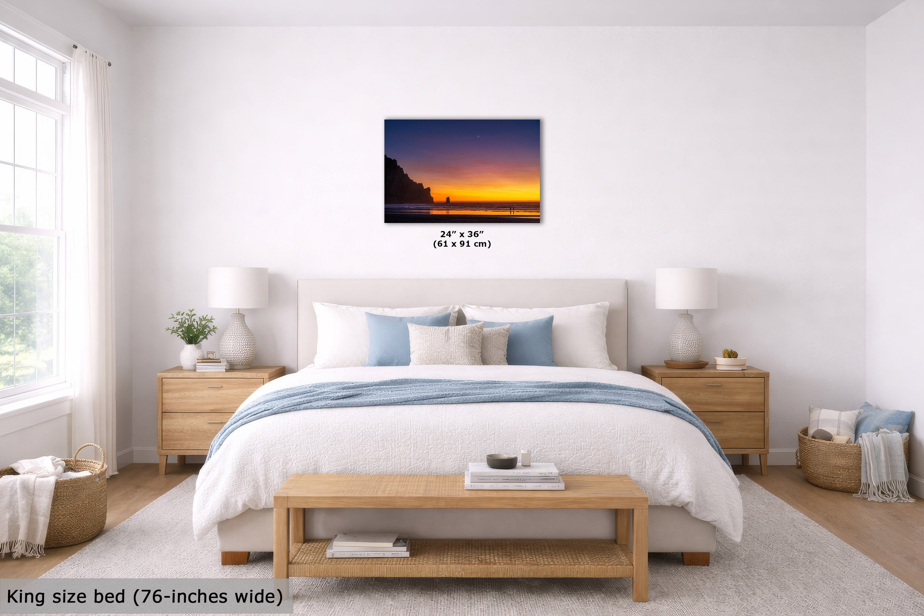 A wall art print showing a dramatic sunset over a dark cliffside shoreline hangs above a neatly made bed in a bright, modern bedroom. The print is labeled as 24 x 36 inches (61 x 91 cm), and the image includes text noting the bed is king size and the print is 76-inches wide.