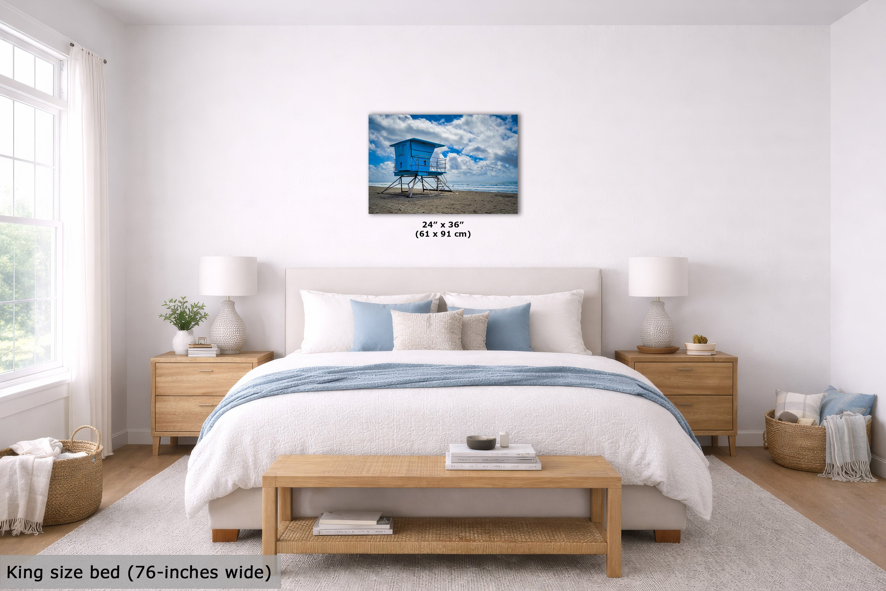 A bedroom scene showing a framed wall art print above a bed. The print depicts a blue beach cabana under a cloudy sky.