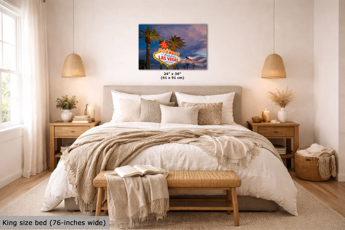 A wall art print showing the Las Vegas sign with palm trees and a sunset sky, displayed above a neatly made bed in a bright, modern bedroom. The print includes size text reading 24 x 36 inches (61 x 91 cm).
