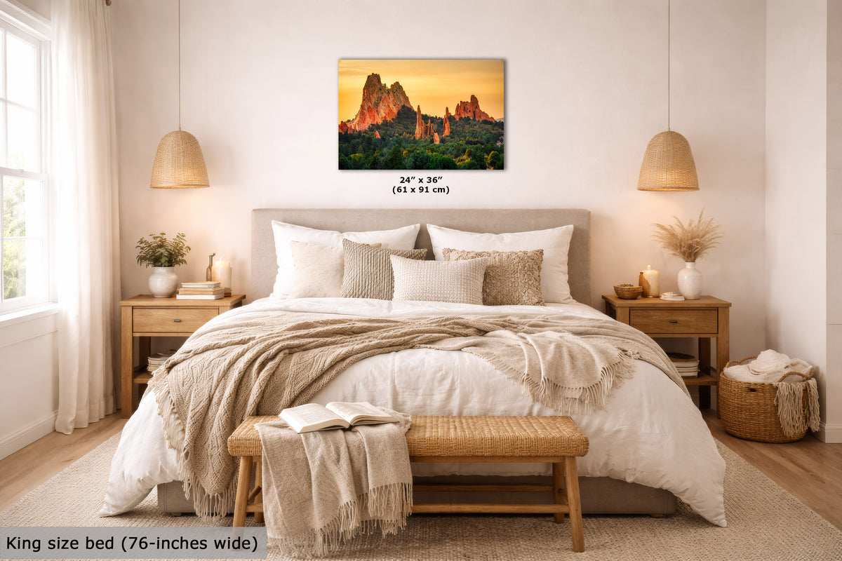 A wall art print showing a desert rock landscape at sunset hangs above a neatly made bed in a warm, modern bedroom. The print includes size text reading 24 x 36 inches, and the room scene is styled with bedding, bedside tables, lamps, and a bench.