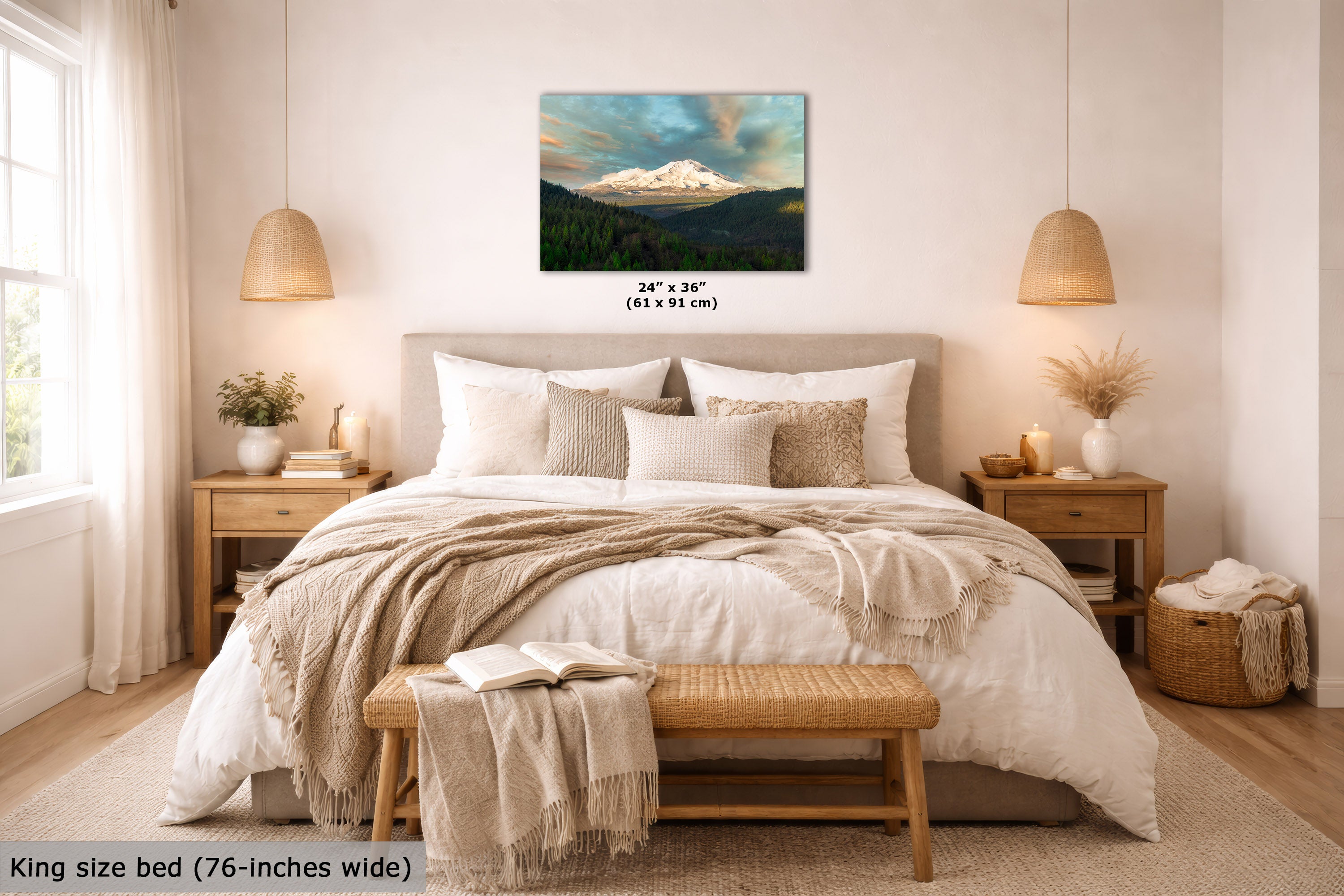 A wall art print showing a snowy mountain over dark green forest, displayed above a neatly made bed in a bright, neutral-toned bedroom. The print includes size text reading 24 x 36 inches (61 x 91 cm), and the room scene also includes bedding, lamps, nightstands, and a bench.