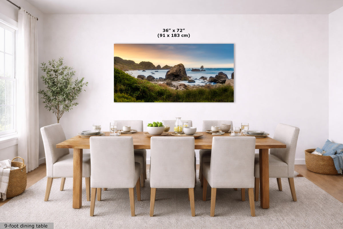 A wall art print showing a coastal rocky shoreline at sunset hangs above a dining table in a bright, modern dining room. The print includes size text reading 36 x 72 inches (91 x 183 cm).