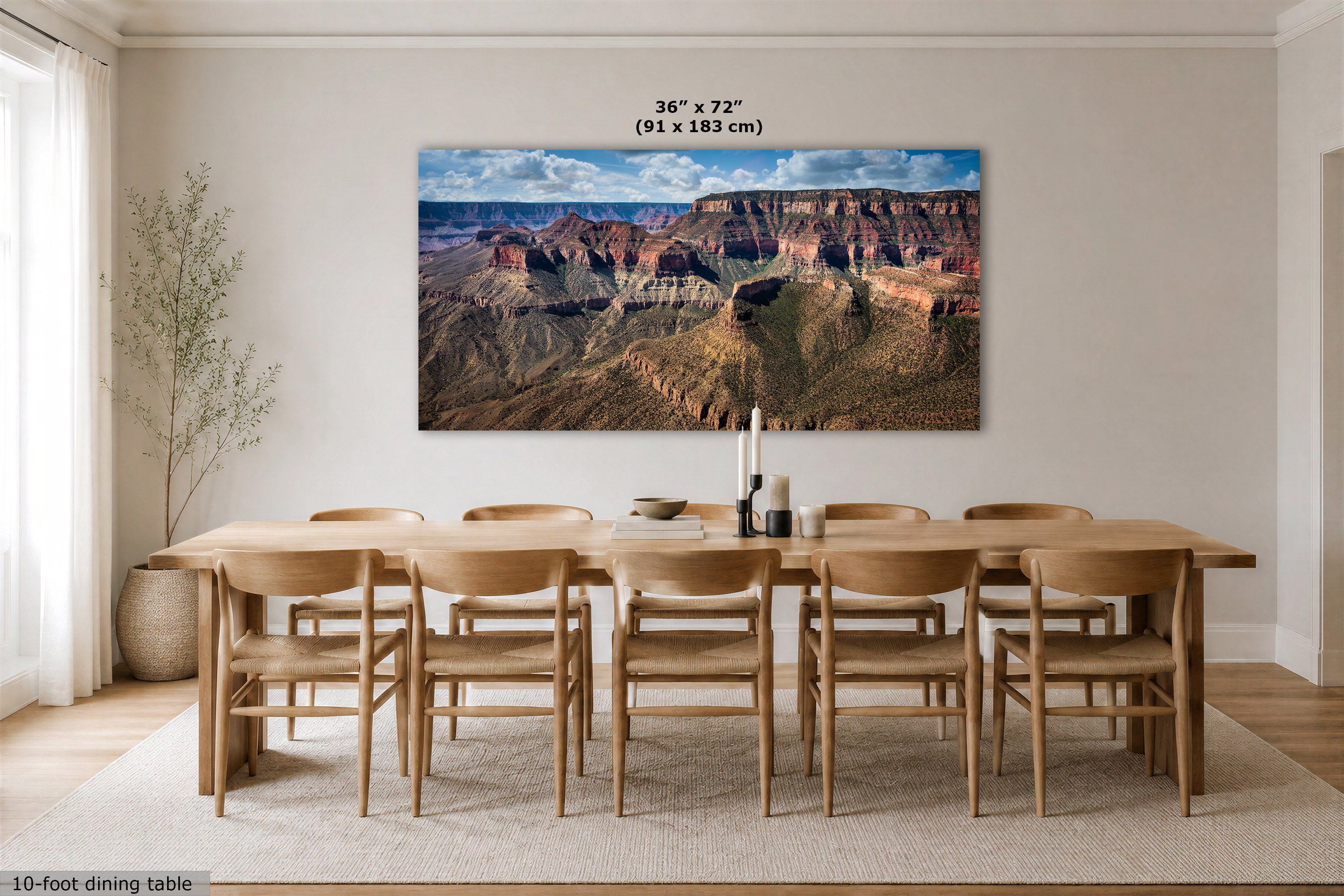 A large rectangular wall art print showing a canyon landscape hangs above a dining table and chairs in a bright, modern dining room. The print includes size text at the top reading 36 x 72" (91 x 183 cm).