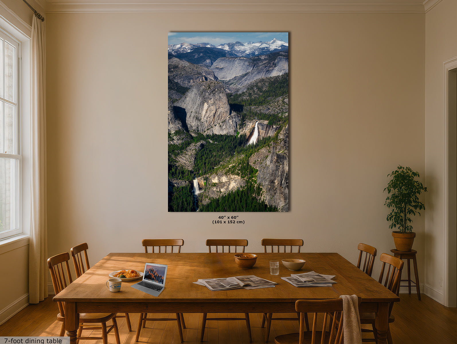 A large vertical Yosemite wall art print depicting a mountain valley landscape with cliffs, forests, and Nevada and Vernal Falls, displayed above a wooden dining table in a beige dining room. The print includes size text reading 40" x 60" (101" x 152").