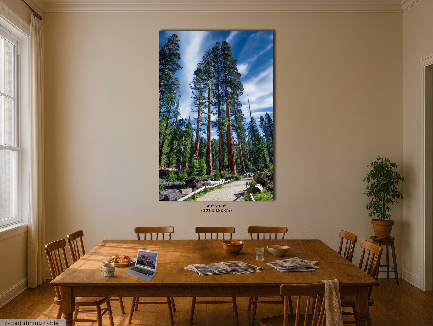 A large vertical wall art print depicting a Giant Sequoia forest scene with tall trees under a blue sky, displayed above a wooden dining table in a beige dining room. The print includes size text reading 48" x 60" (122 x 152 cm).
