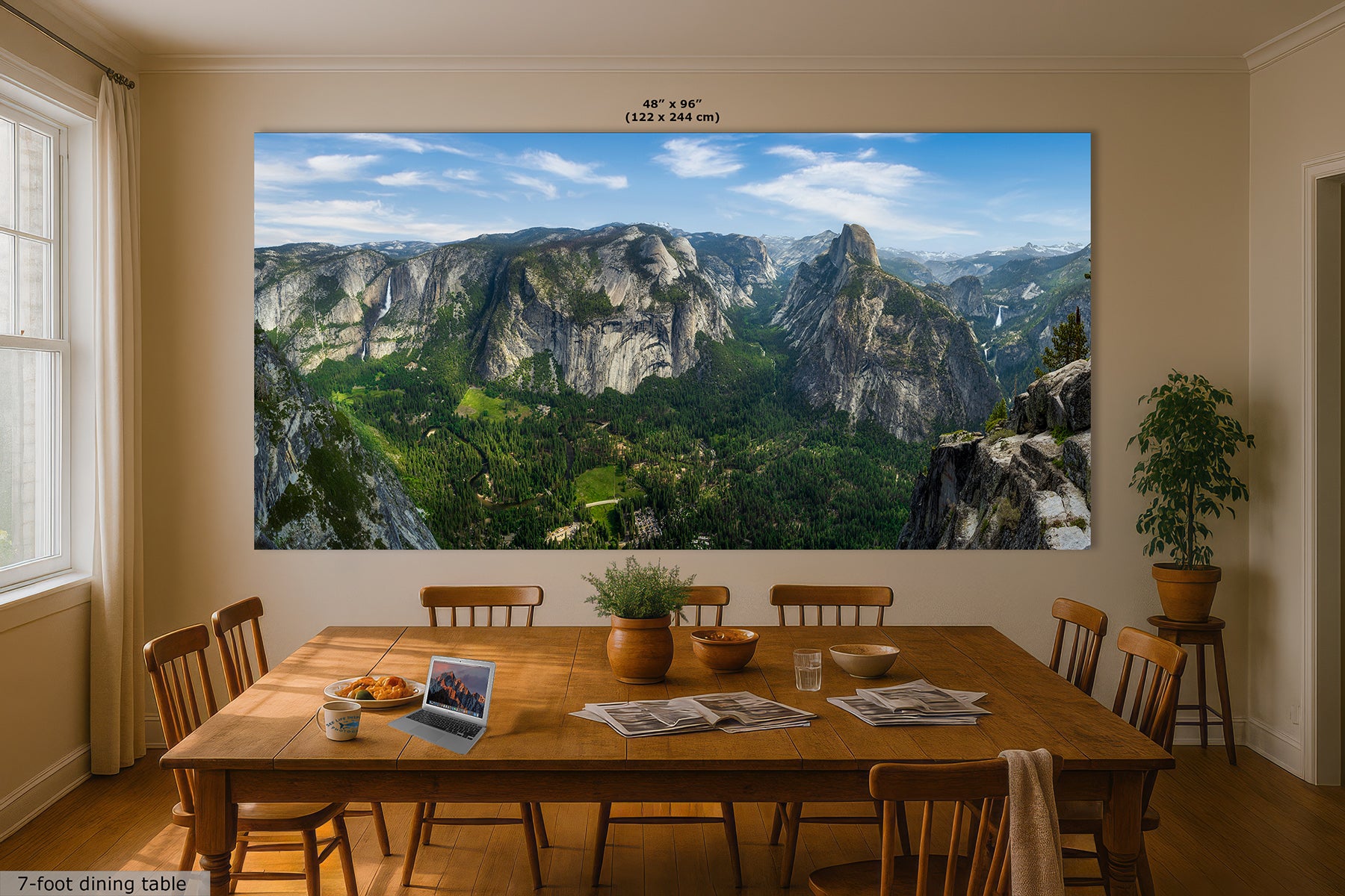 A large wall art print showing a mountain valley landscape of Yosemite Valley and Half Dome from Glacier Point with green forests and rocky cliffs, displayed above a wooden dining table in a styled dining room. The print includes size text at the top, reading "48" x "96" (122 x 244 in).