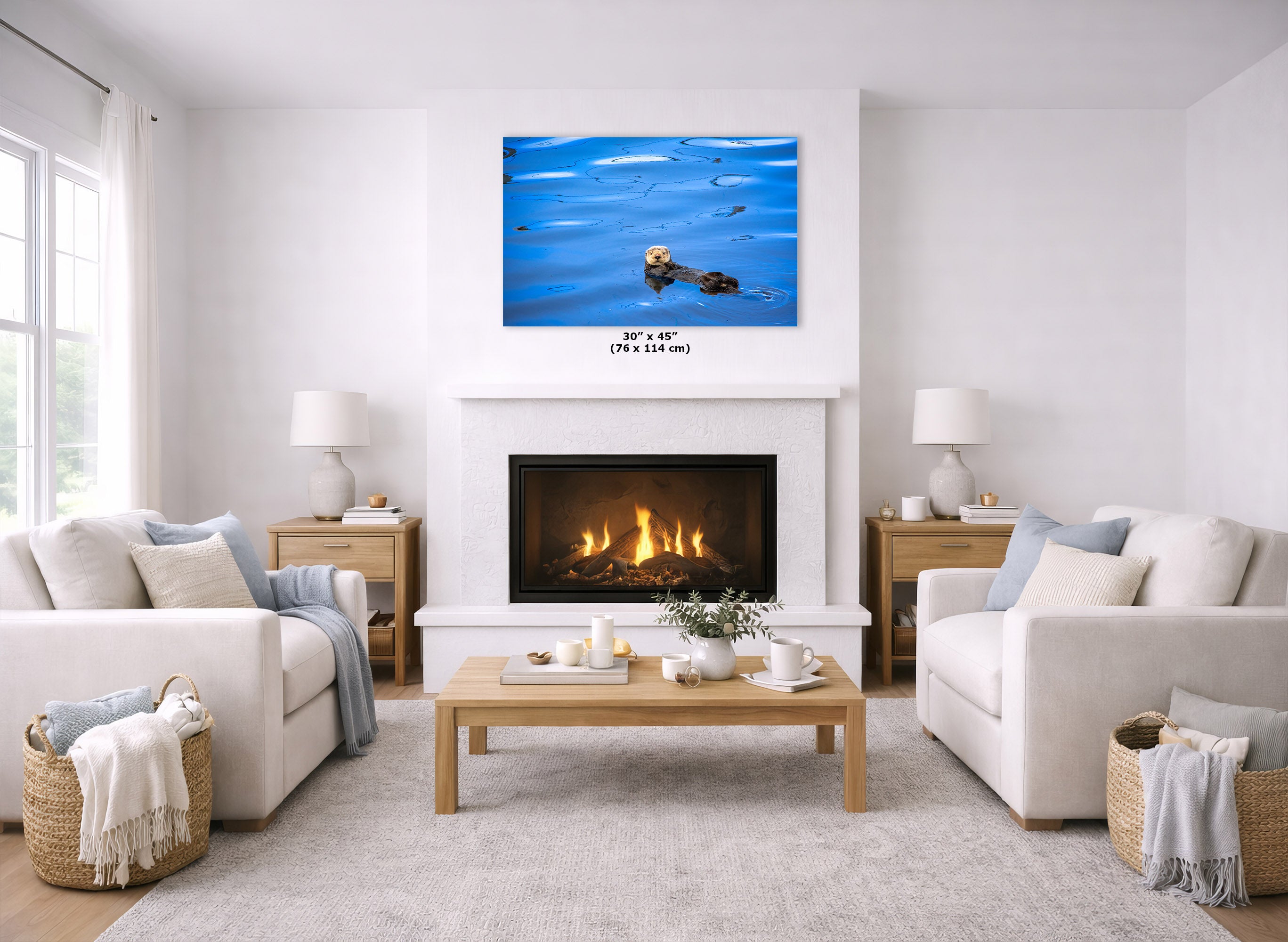 A canvas print of a blue water scene with a small otter floating in the water, displayed above a white fireplace in a bright, modern living room with two white sofas and a wooden coffee table.