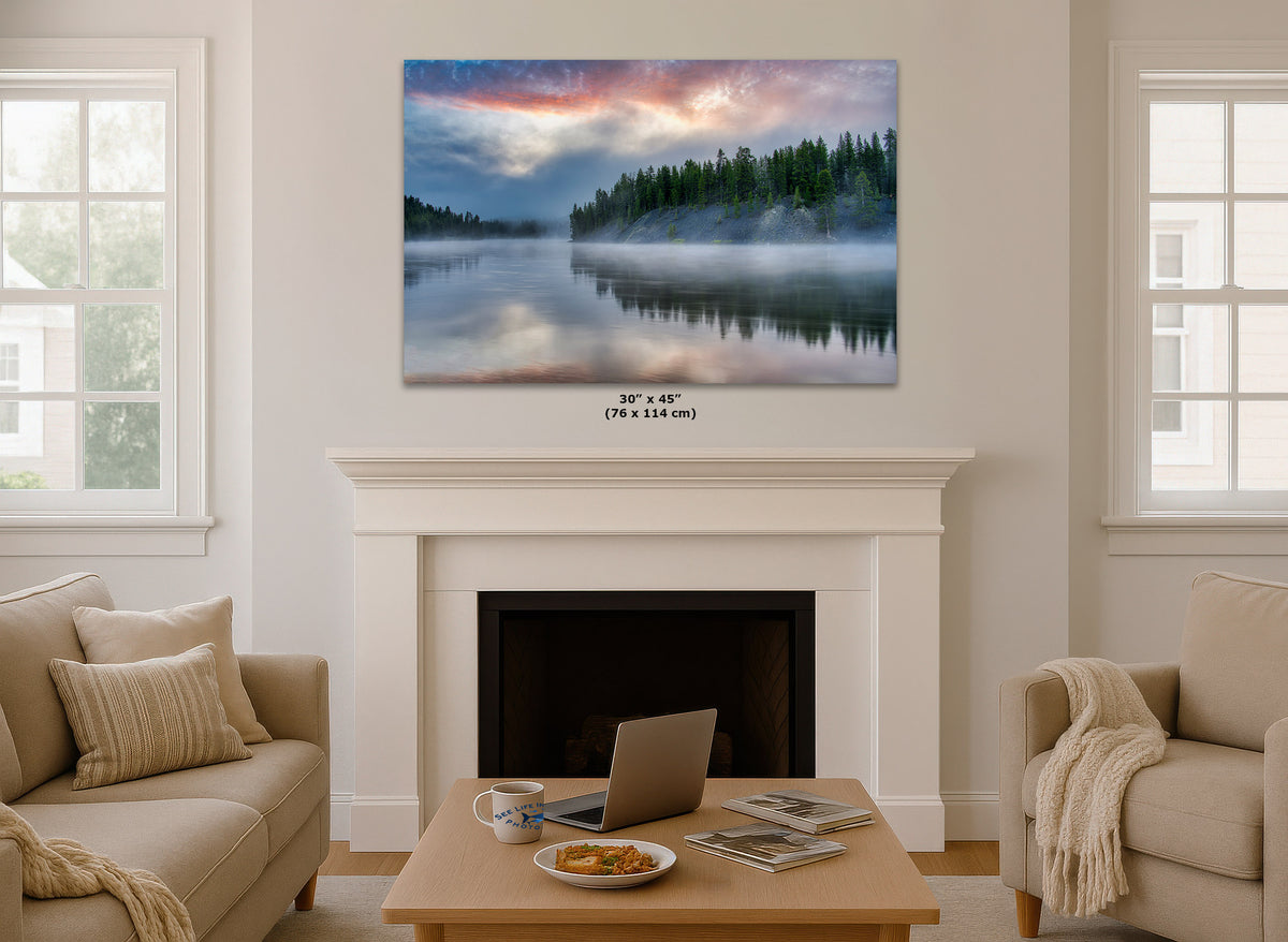 A wall art print showing a misty lake landscape with a forest and colorful sky, displayed above a white fireplace mantel in a bright living room. Small text below the print reads 30 x 45 (76 x 114 in).