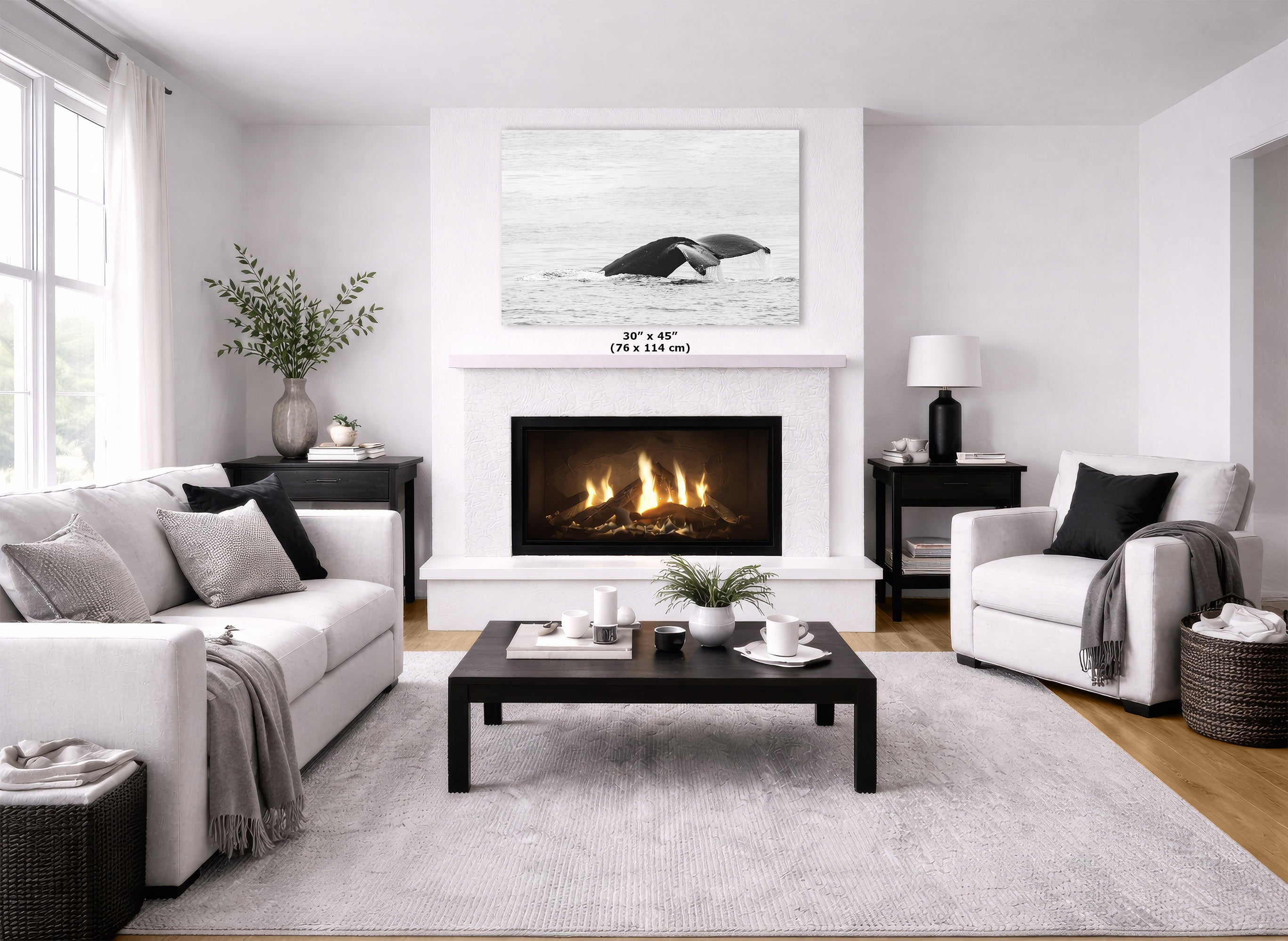 A modern living room featuring a large black and white whale print on the wall above a fireplace. The room is styled with a white sofa, a white armchair, a dark wood coffee table, and a light gray rug.