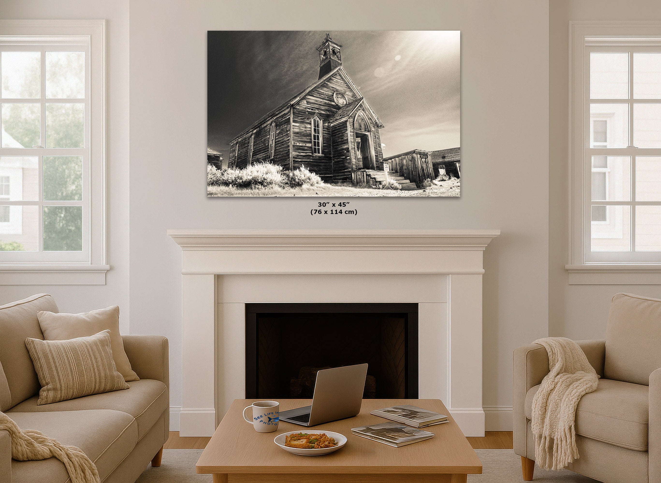 A large vintage canvas wall art print depicting an old wooden church, displayed in a mockup living room setting above a white fireplace mantel.