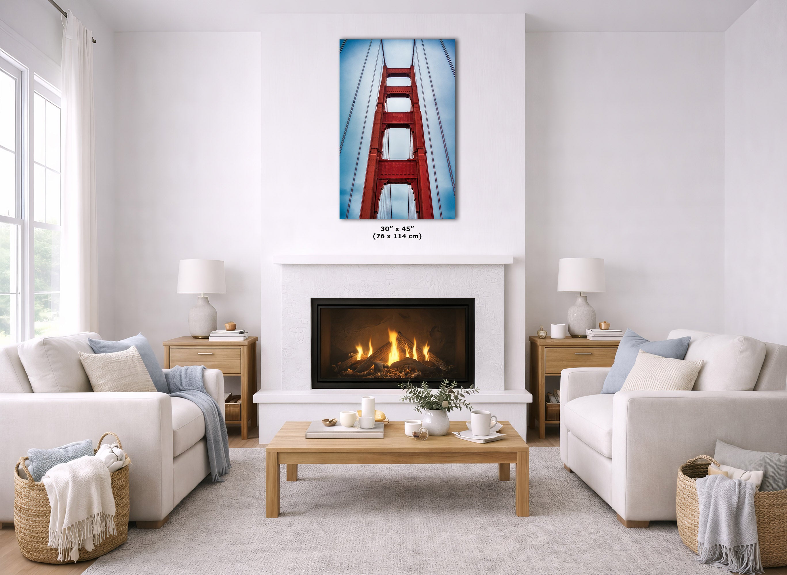 A framed wall art print of the Golden Gate Bridge in red and blue tones, displayed above a fireplace in a bright, modern living room with white sofas, a wooden coffee table, and neutral decor.