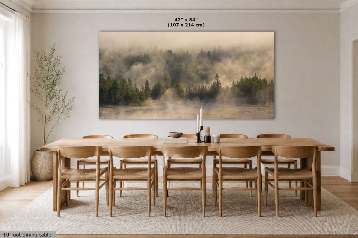 A large rectangular wall art print showing a misty forest landscape in muted green, brown, and beige tones, displayed above a wooden dining table and chairs in a bright modern dining room. Text at the top reads 42" x 84" (107 x 214 cm), and text at the bottom left says 10-foot dining table.