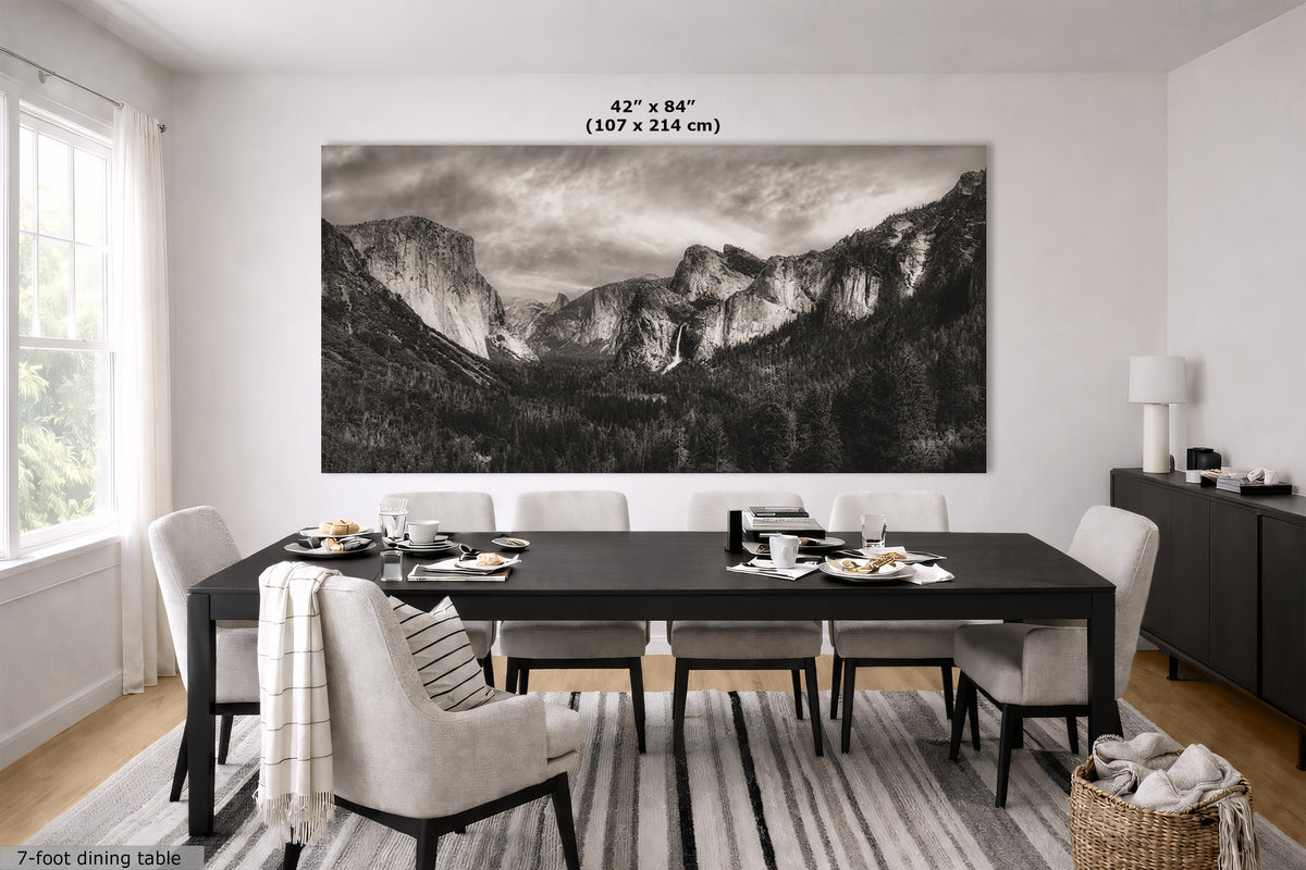 A large black and white landscape wall art print depicting a mountain valley, displayed above a dark dining table in a bright, modern dining room. The image includes a size measurement overlay at the top of the print.