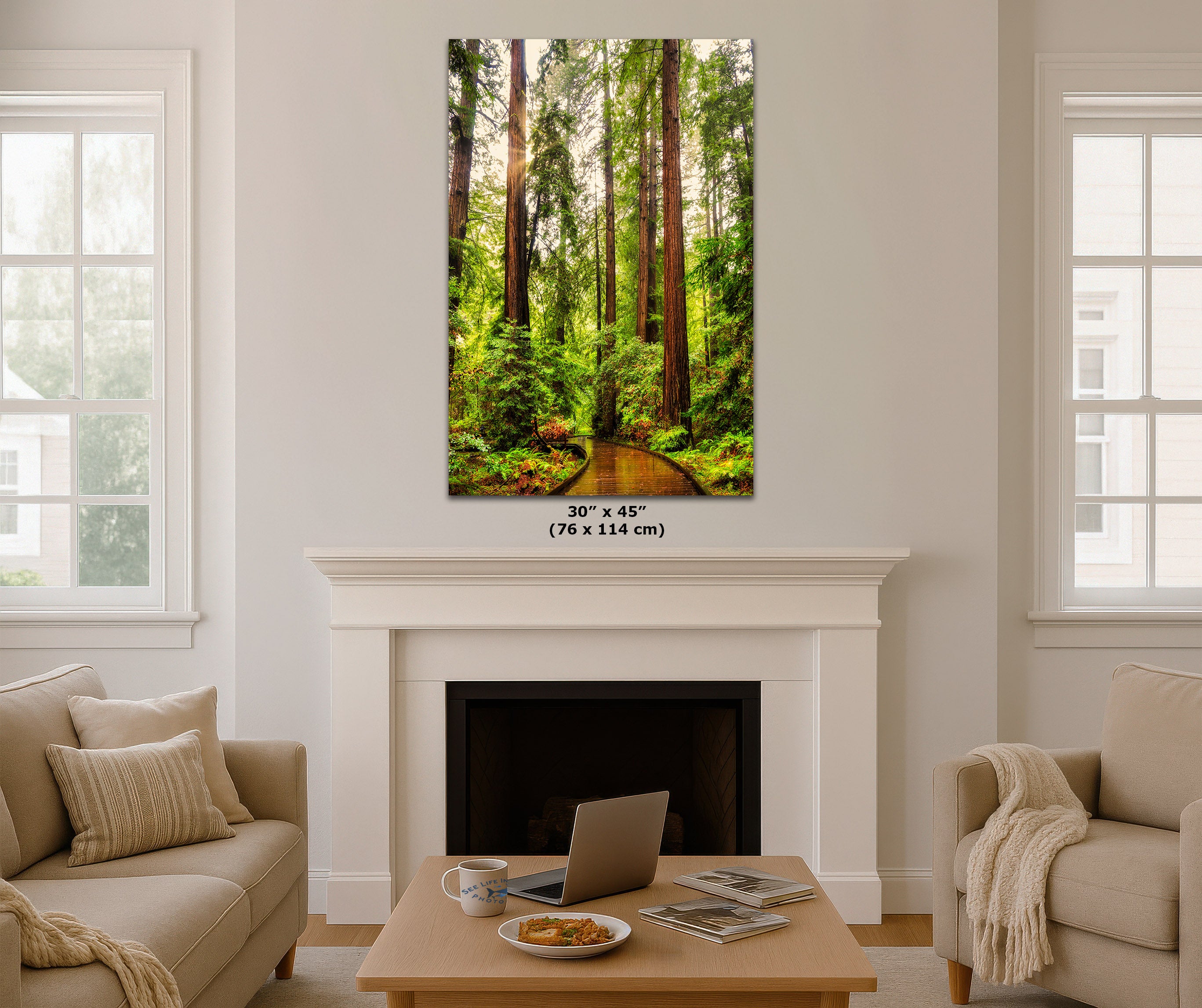 A vertical canvas wall art print depicting a lush green forest with tall trees and a winding path, displayed above a white fireplace mantel in a modern living room setting. The print features a size dimension label of 30 x 45 inches (76 x 114 cm) printed directly on the image.