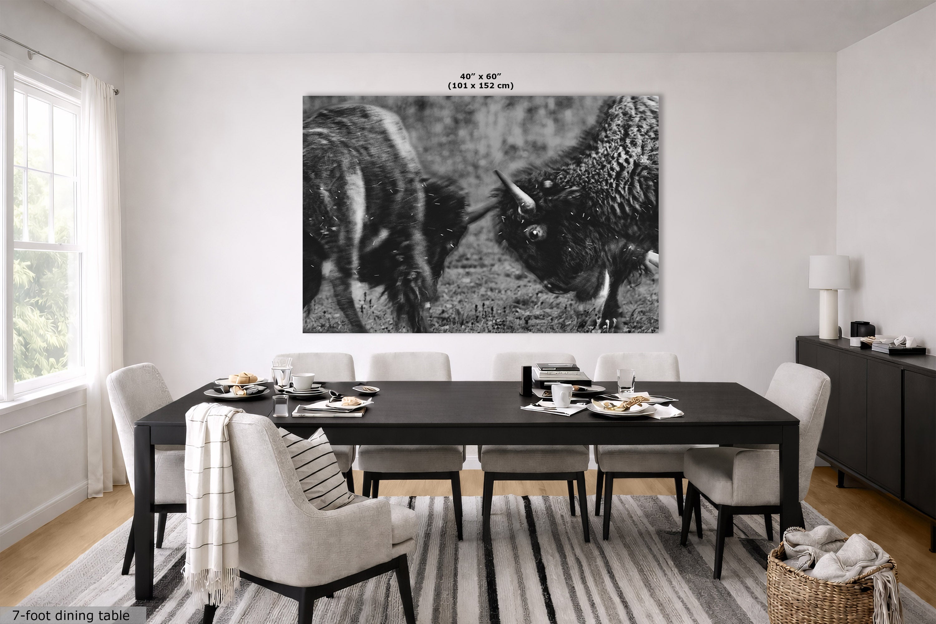A large black and white wall art print depicting two bison facing each other, displayed in a modern dining room setting above a dark wood dining table and chairs.