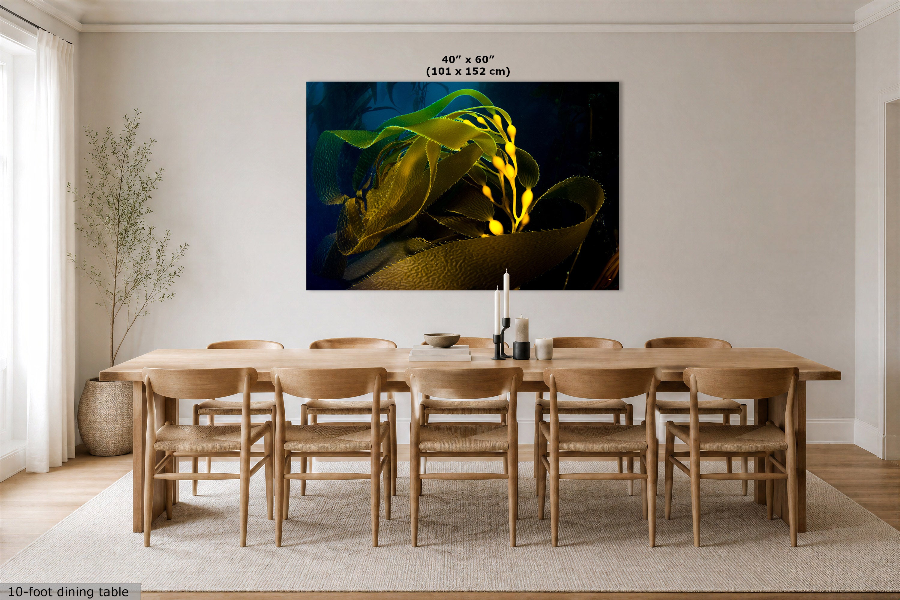 A large rectangular wall art print showing a dark abstract floral or organic scene with bright yellow-green highlights, displayed above a wooden dining table and chairs in a modern dining room. Text at the top of the print reads 40" x 60" (101 x 152 cm), and a small caption at the bottom left says 10-foot dining table.