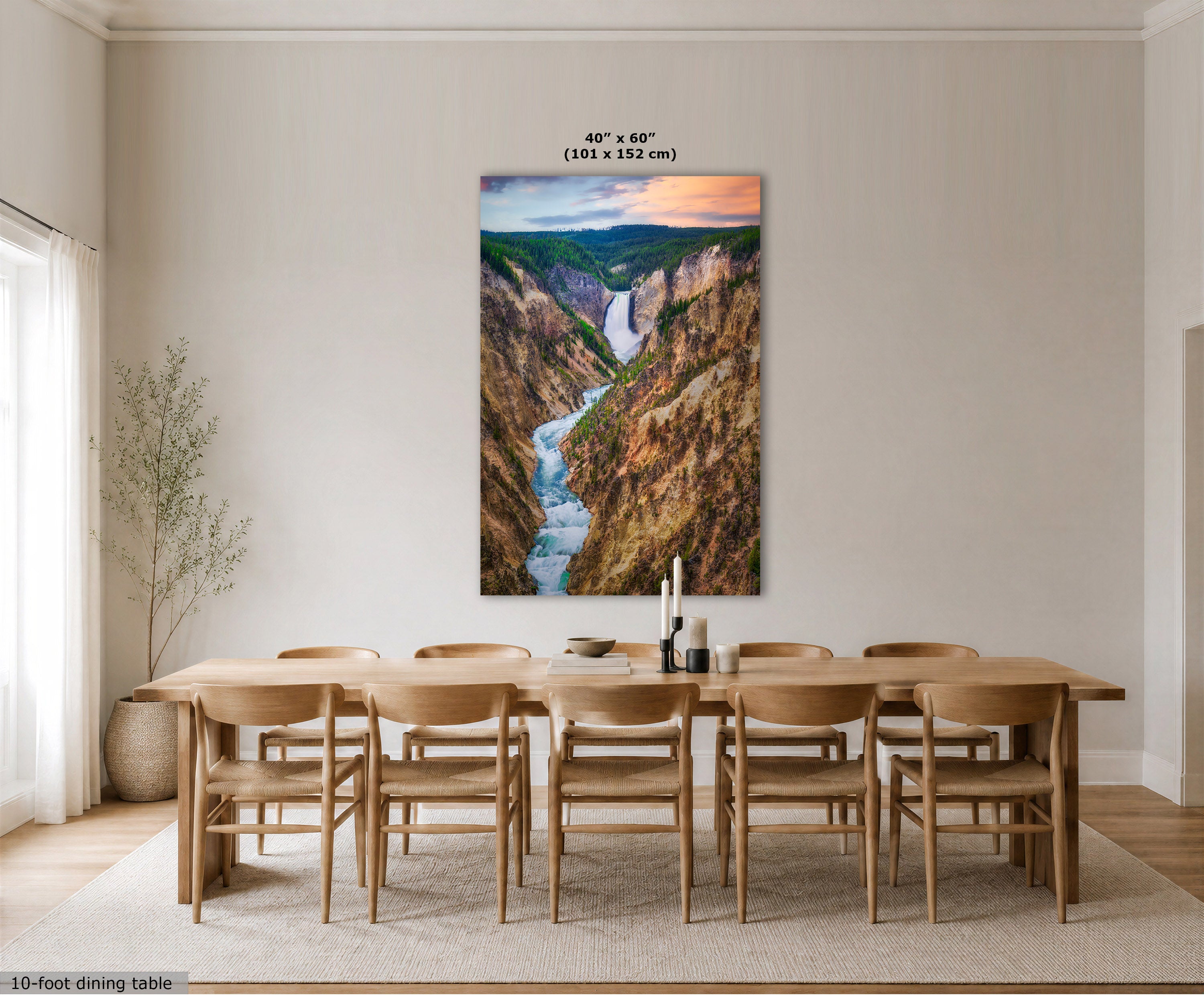 A large vertical canvas print of a deep canyon with a winding river, displayed on a beige wall above a wooden dining table and chairs in a modern dining room. The print features a colorful sunset sky and has dimension text above it reading 40" x 60" (101 x 152 cm).