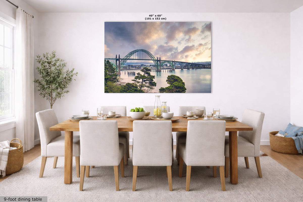 A large rectangular wall art print showing a bridge over water at sunset, displayed above a dining table in a bright modern dining room. The print includes size text reading 40" x 60" (101 x 152 cm).