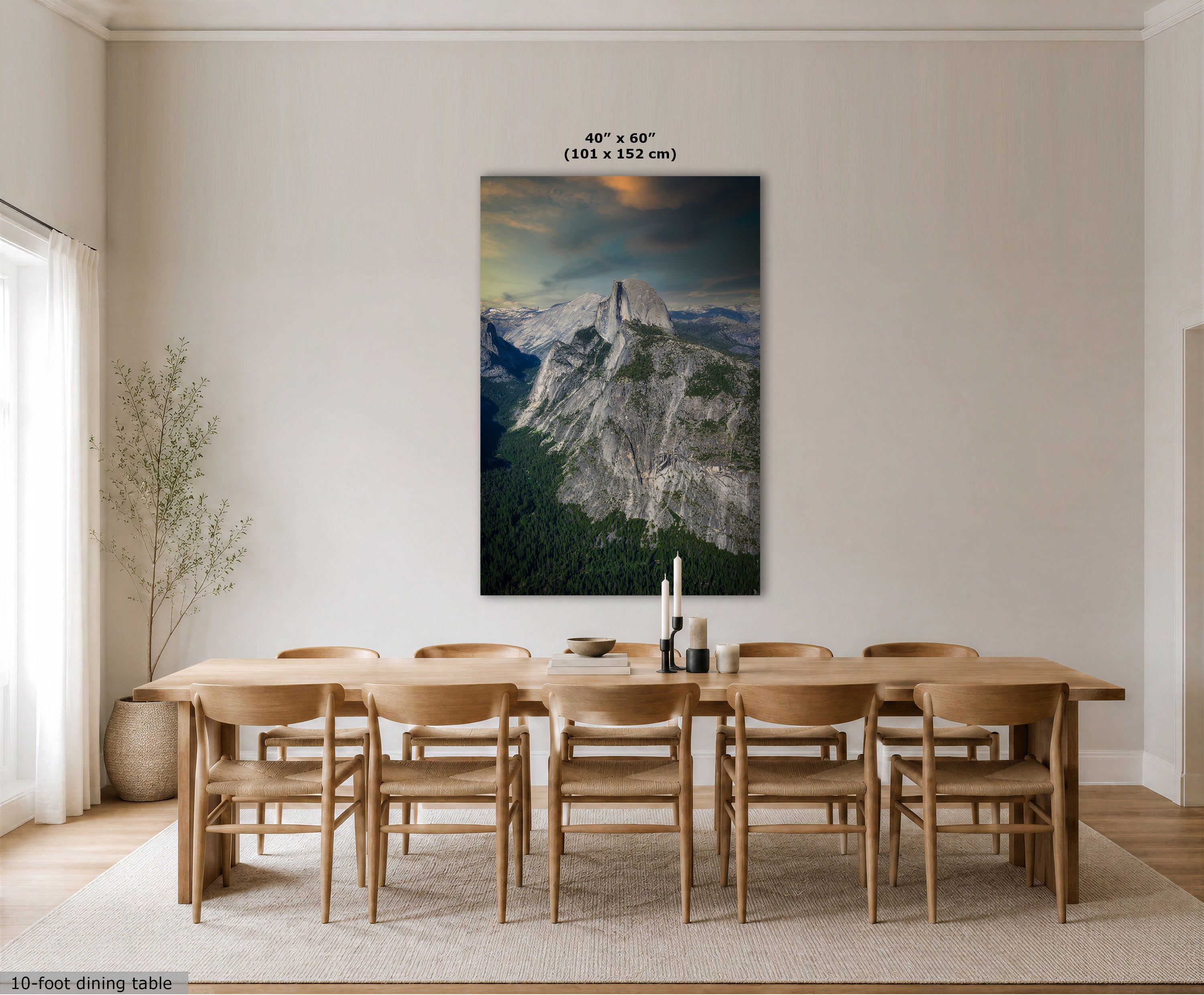 A large vertical wall art print showing a mountain landscape with a glowing sunset, displayed above a wooden dining table and chairs in a bright neutral dining room. Text at the top reads 40 x 60" (101 x 152 cm).