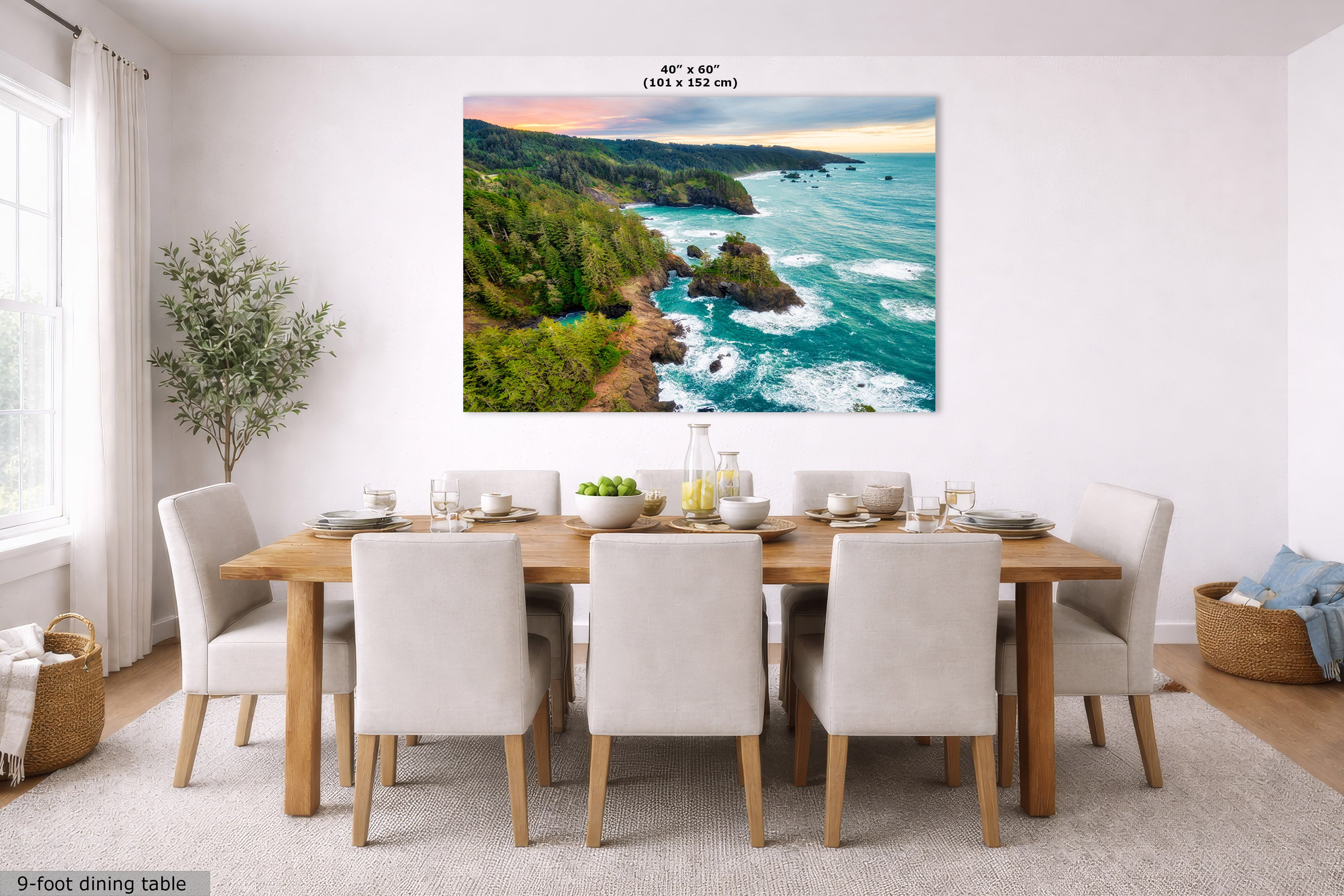 A large square wall art print showing a coastal landscape with turquoise ocean waves, rocky cliffs, and green hills under a sunset sky, displayed above a dining table in a bright modern room. Text at the top reads 40" x 60".