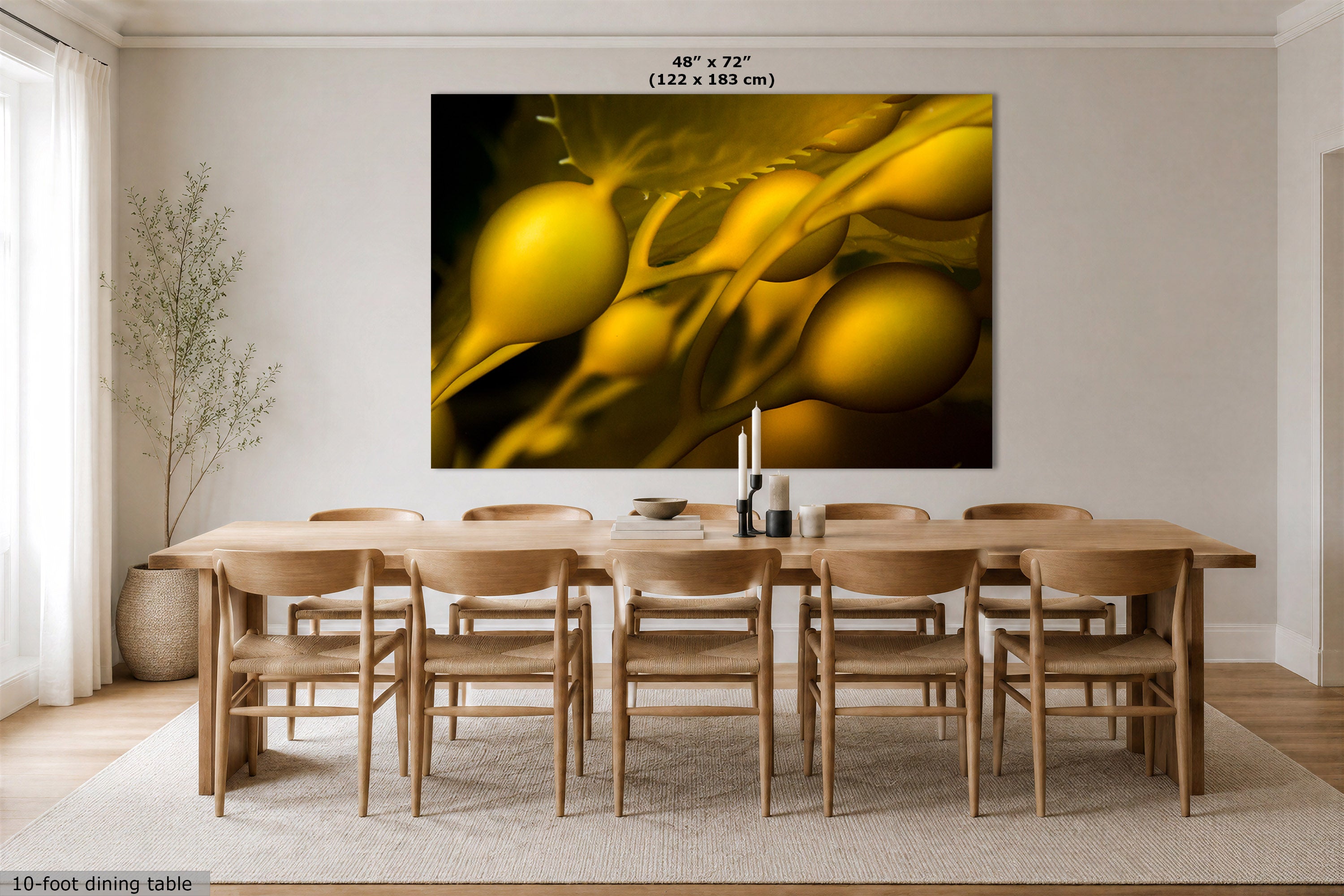 A large wall art print showing abstract golden-yellow organic forms on a dark background, displayed above a wooden dining table and chairs in a bright modern dining room. Text at the top reads 48" x 72" (122 x 183 cm).