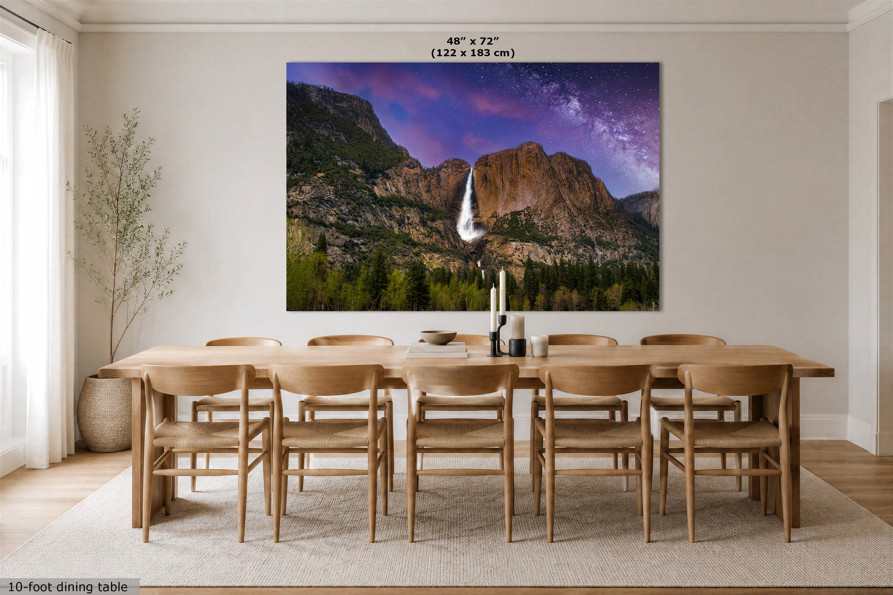 A large wall art print showing a mountain landscape with a waterfall under a purple sky, displayed above a wooden dining table and chairs in a bright dining room. Text at the top reads 48" x 72" (122 x 183 cm).