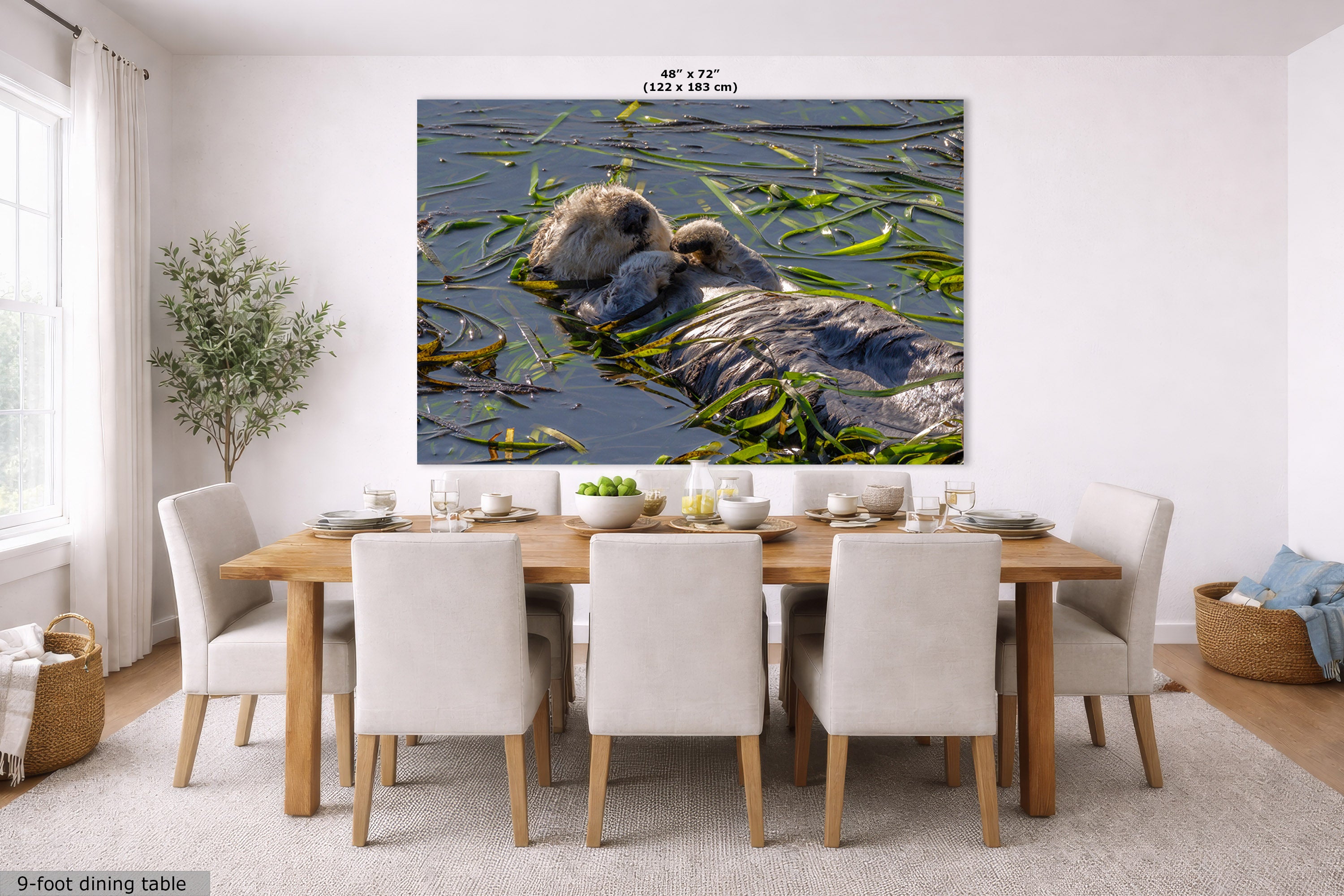 A large wall art print showing a otter floating in water with green reeds, displayed above a dining table in a bright modern room. Small text at the top of the print reads 48" x 72".