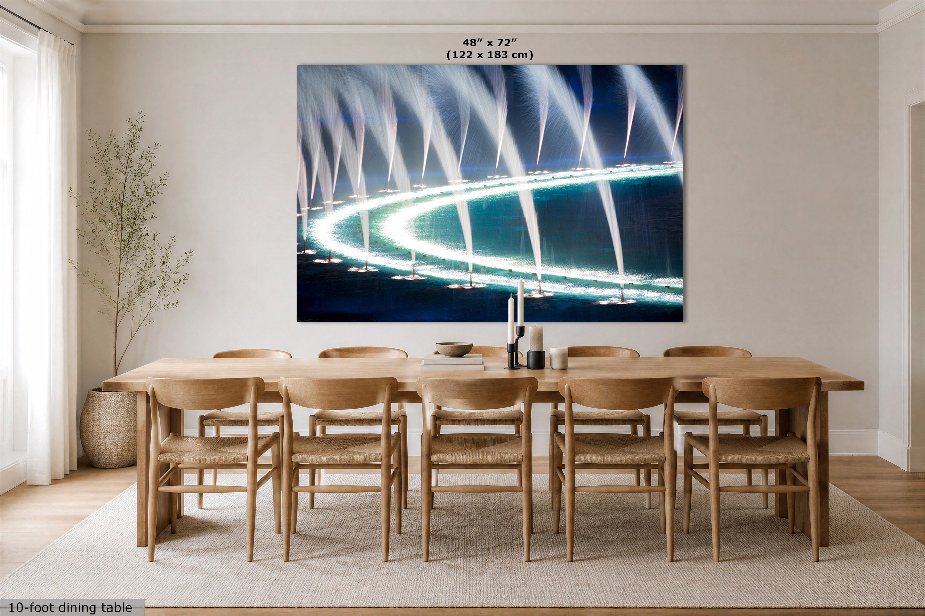 A large wall art print showing a curved illuminated pathway or fountain-like light display in blue, white, and black tones, displayed above a wooden dining table and chairs in a bright modern dining room. Text at the top reads 48" x 72" (122 x 183 cm), and a small note at the bottom left says 10-foot dining table.
