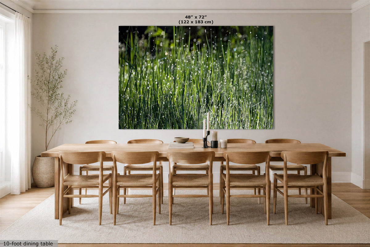 A large wall art print showing green grass with dew drops, displayed above a wooden dining table and chairs in a bright neutral dining room. Text at the top reads 48" x 72" (122 x 183 cm), and text at the bottom left says 10-foot dining table.