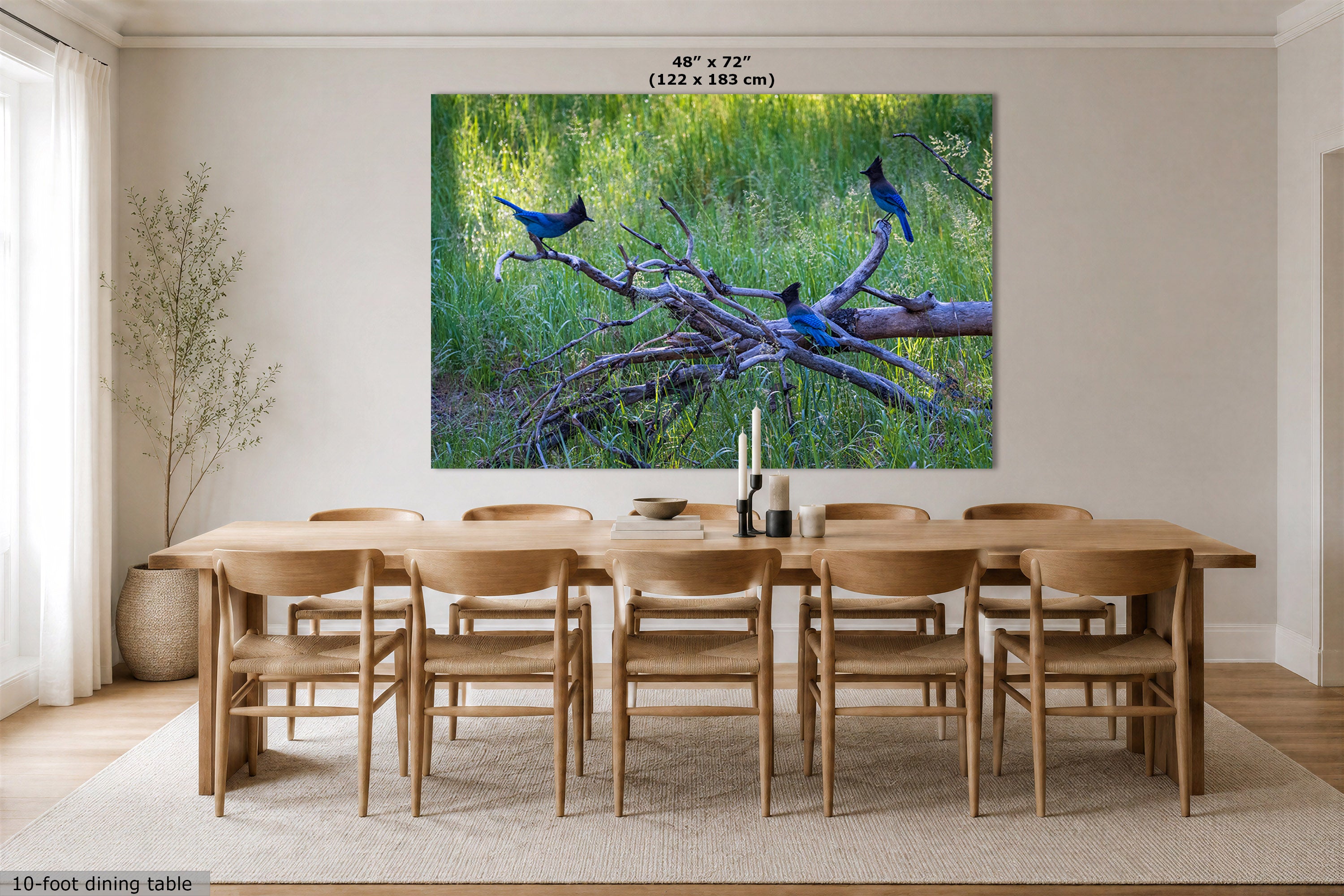 A large wall art print showing bluebirds perched on branches in a grassy green setting, displayed above a wooden dining table and chairs in a bright dining room. Text at the top of the print reads 48" x 72" (122 x 183 cm).