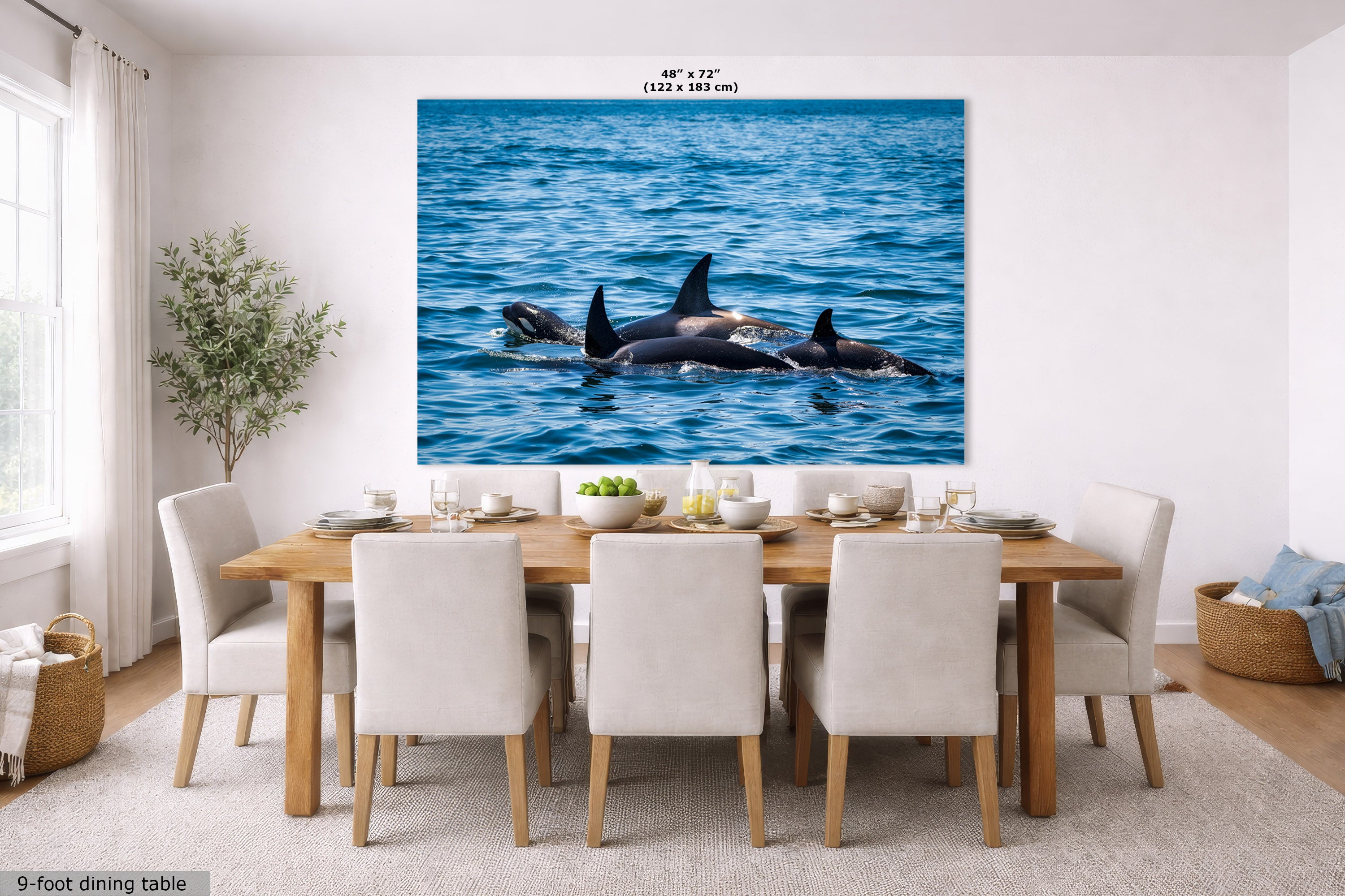 A large wall art print showing a group of orcas swimming in blue ocean water, displayed above a dining table in a bright modern room. The print includes size text at the top and a small label at bottom left.