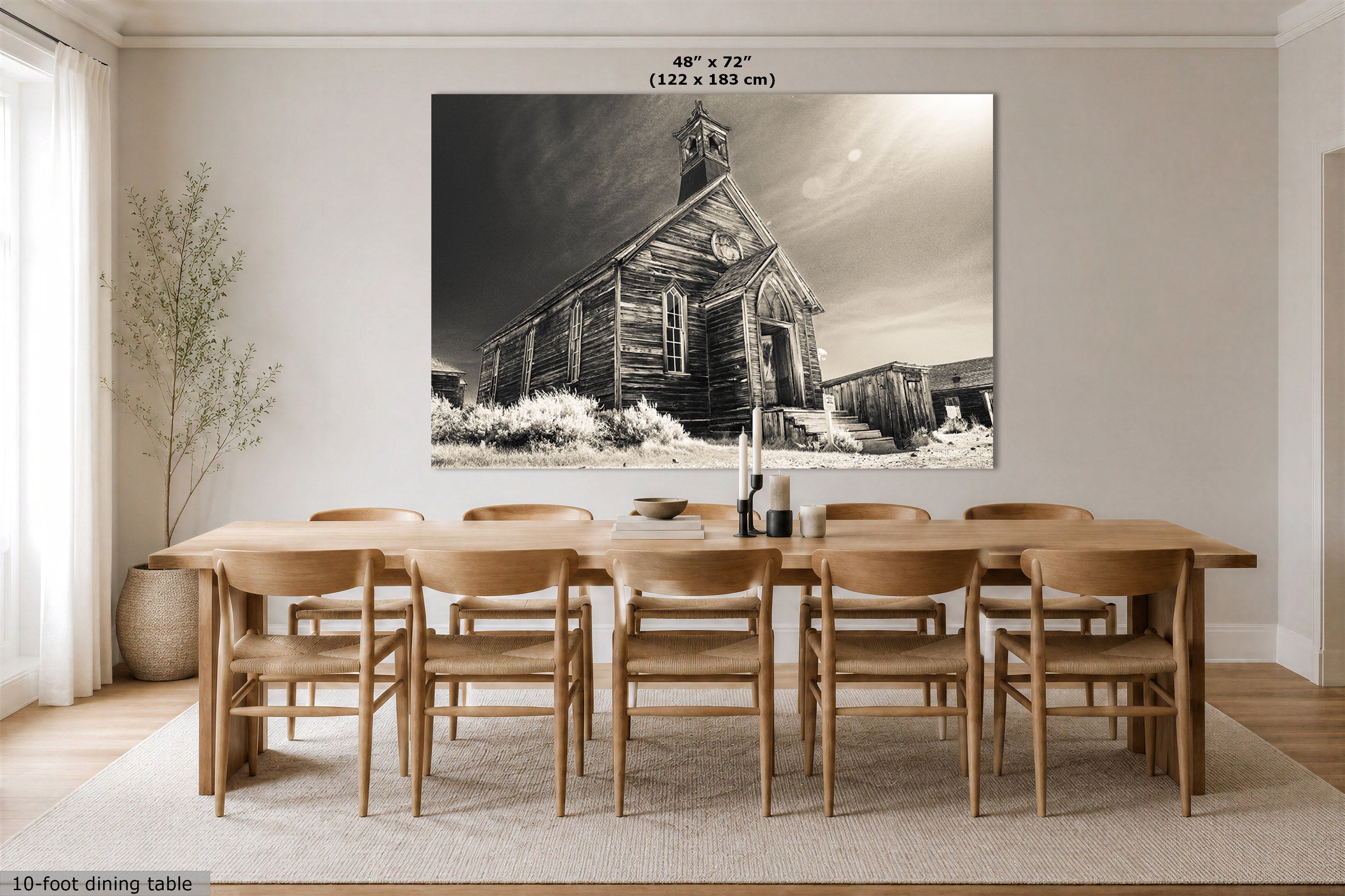 A large black and white canvas wall art print depicting a dilapidated old chruch, shown hanging on a dining room wall above a wooden dining table and chairs. The image includes a size label at the top of the print.