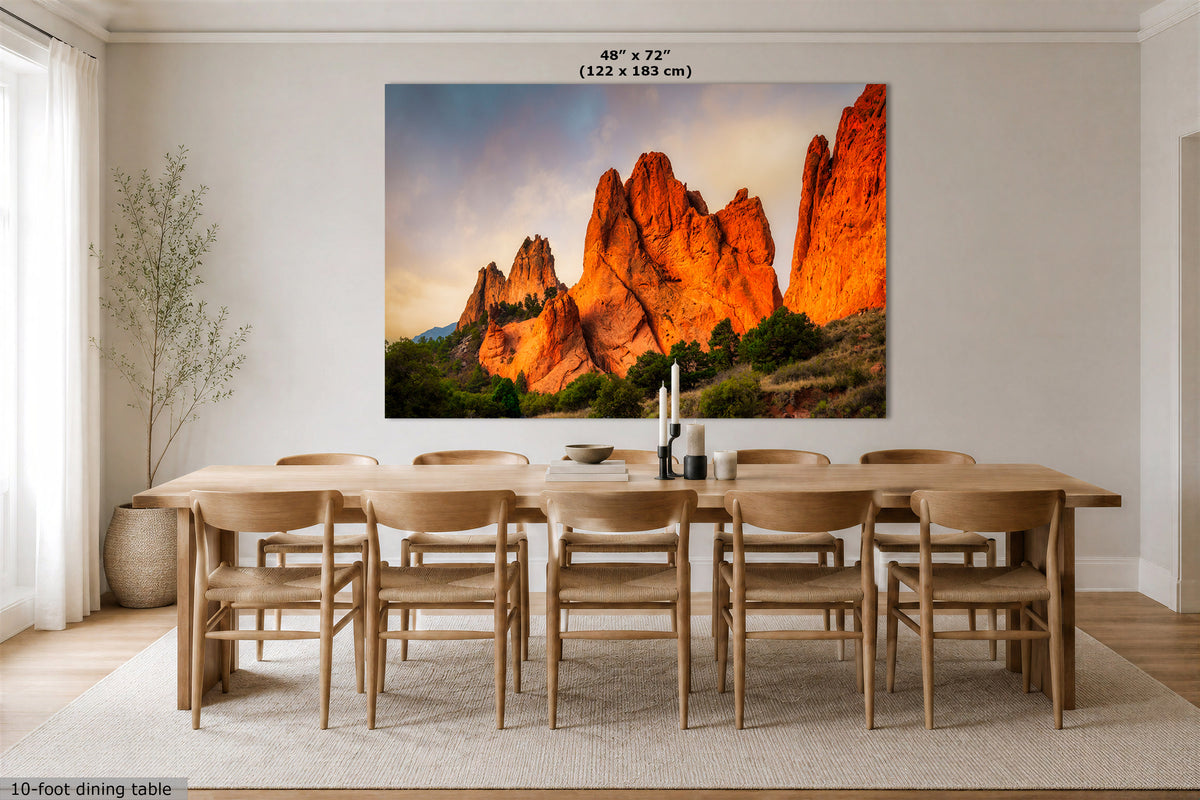 A large wall art print depicting orange rock desert cliffs at sunset, displayed above a wooden dining table and chairs in a bright modern dining room. Text at the top indicates the print size as 48 x 72 inches (122 x 183 cm).