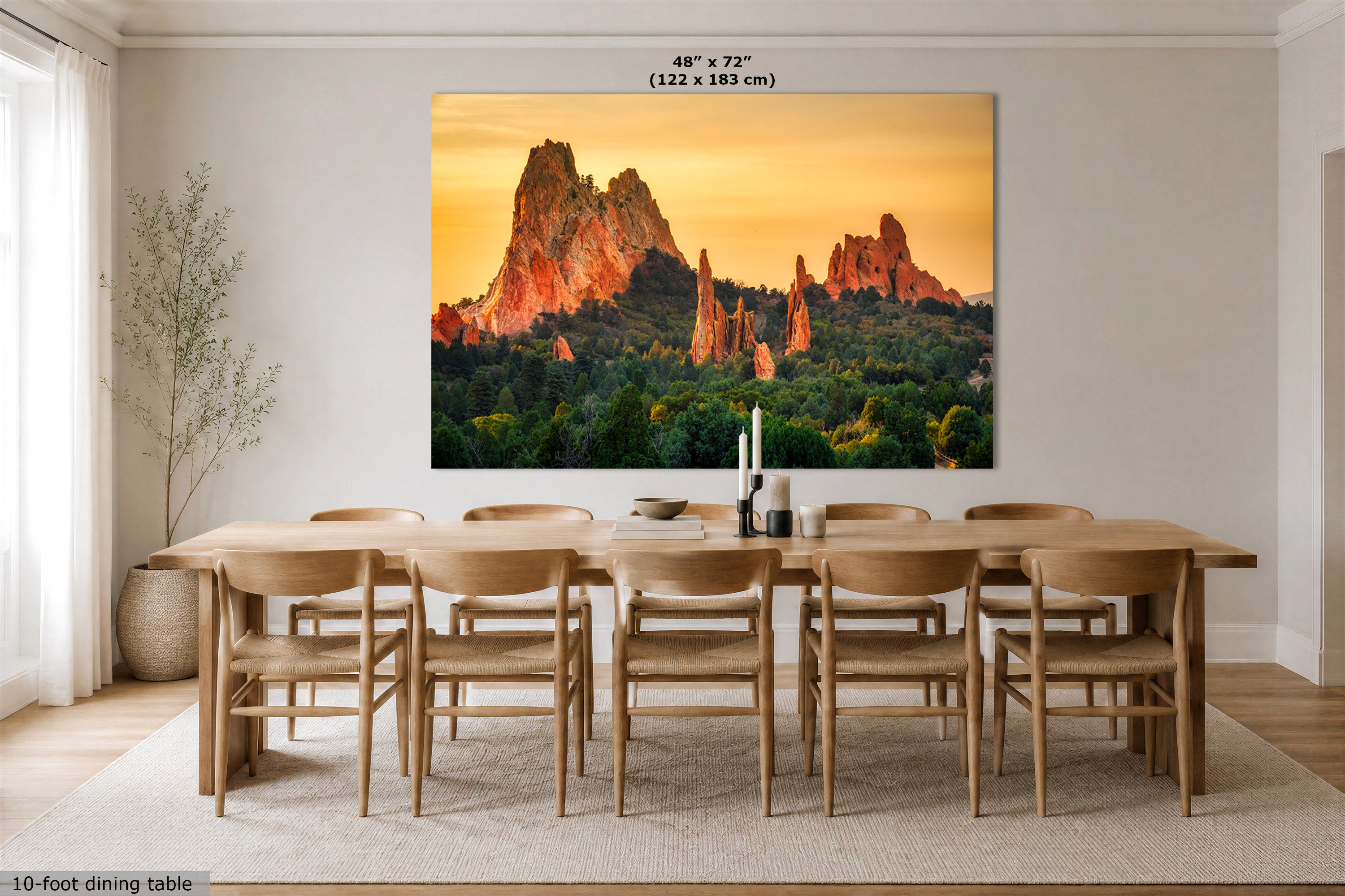 A large wall art print showing a desert rock formation landscape at sunset, displayed above a wooden dining table and chairs in a bright modern dining room. Text at the top indicates the print size as 48" x 72" (122 x 183 cm).