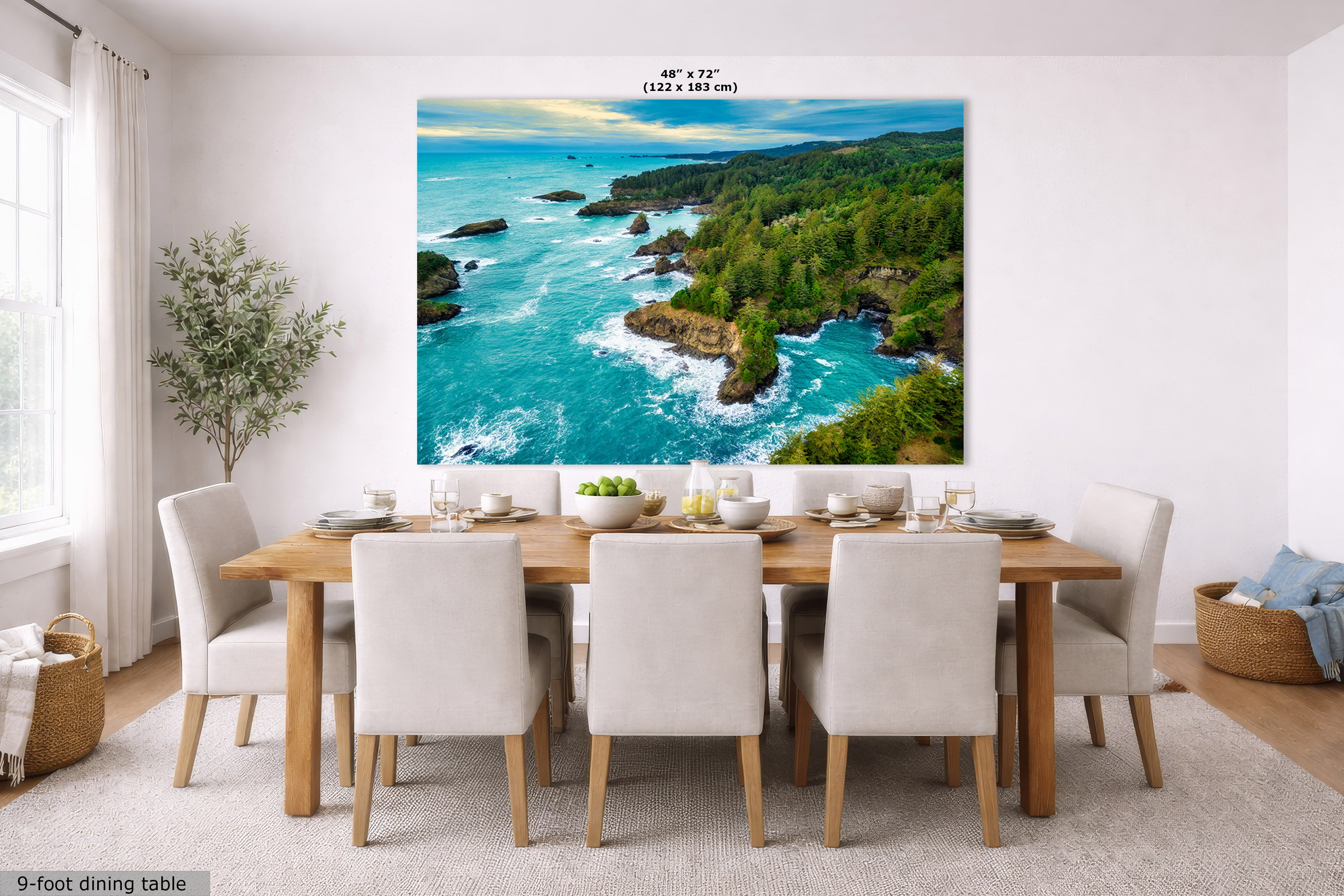 A large wall art print showing a coastal ocean landscape with turquoise water, rocky shoreline, and green forest, displayed above a dining table in a bright modern room. Text at the top reads 48" x 72" (122 x 183 cm), and a small label at bottom left says 9-foot dining table.