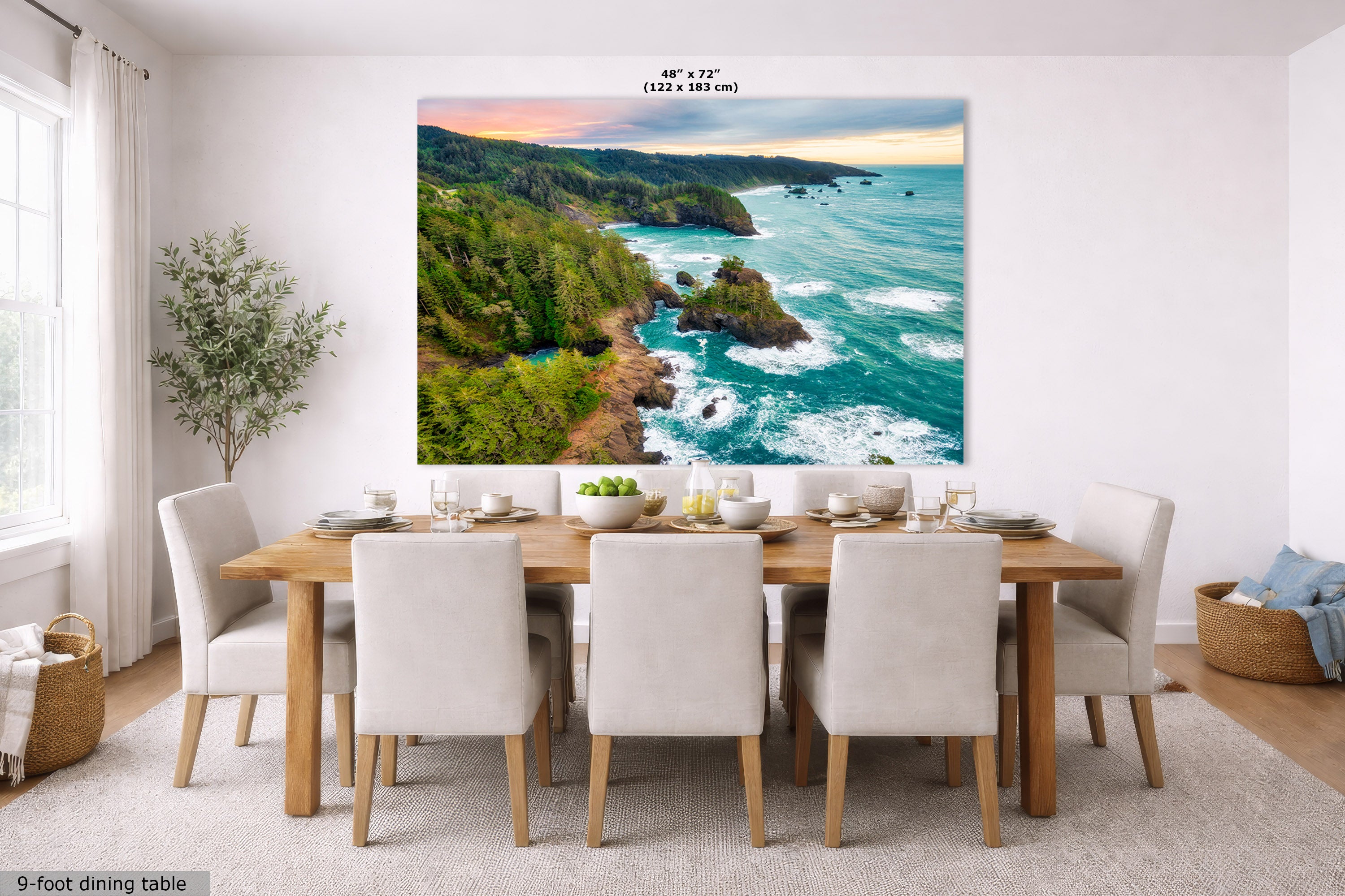 A large wall art print showing a coastal landscape with turquoise ocean waves, rocky cliffs, and green forest, displayed above a dining table in a bright modern room. Small text at the top reads 48" x 72".