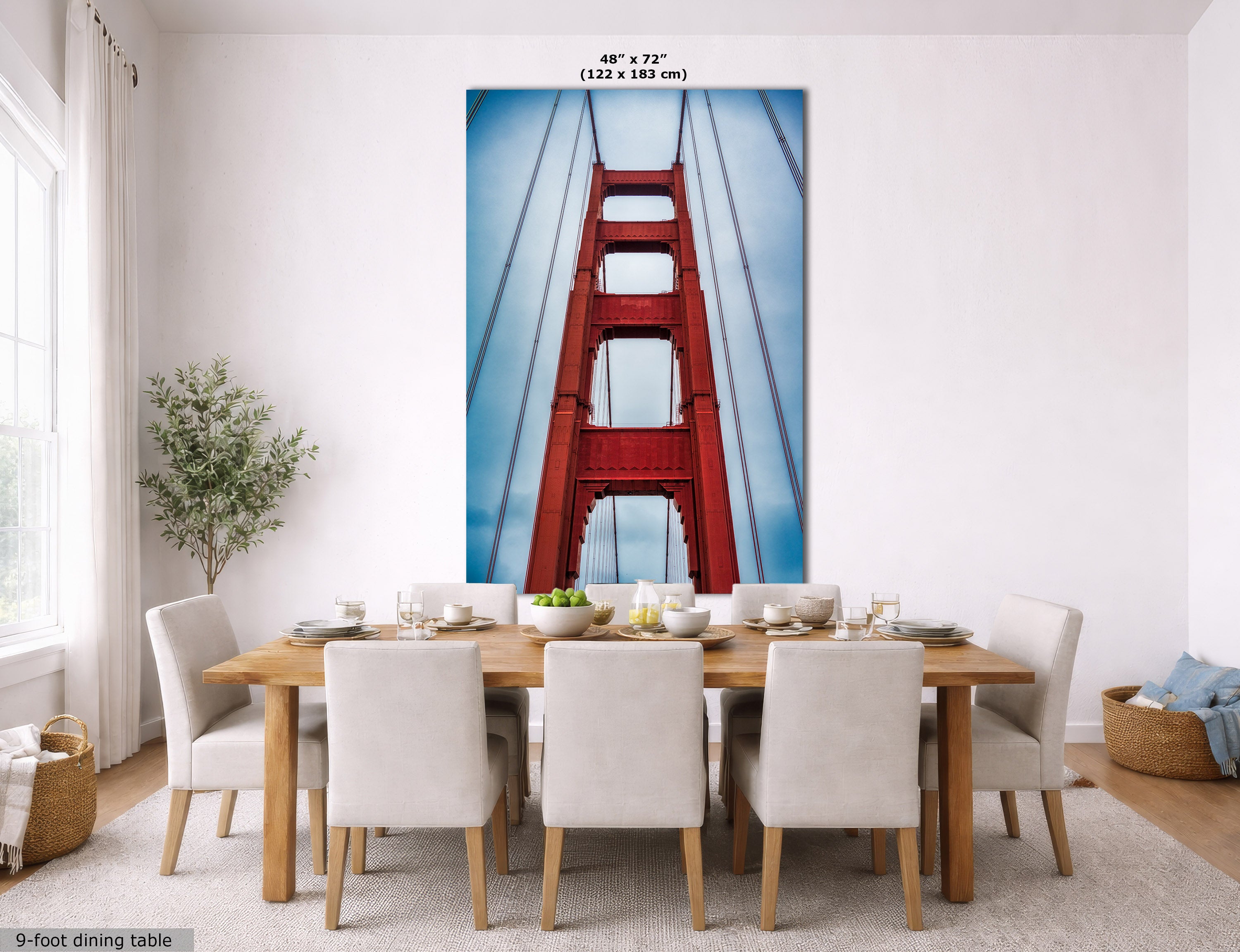 A large wall mural of the Golden Gate Bridge is displayed on a dining room wall above a wooden dining table and chairs. The mural features a close-up view of the red bridge towers against a blue sky.