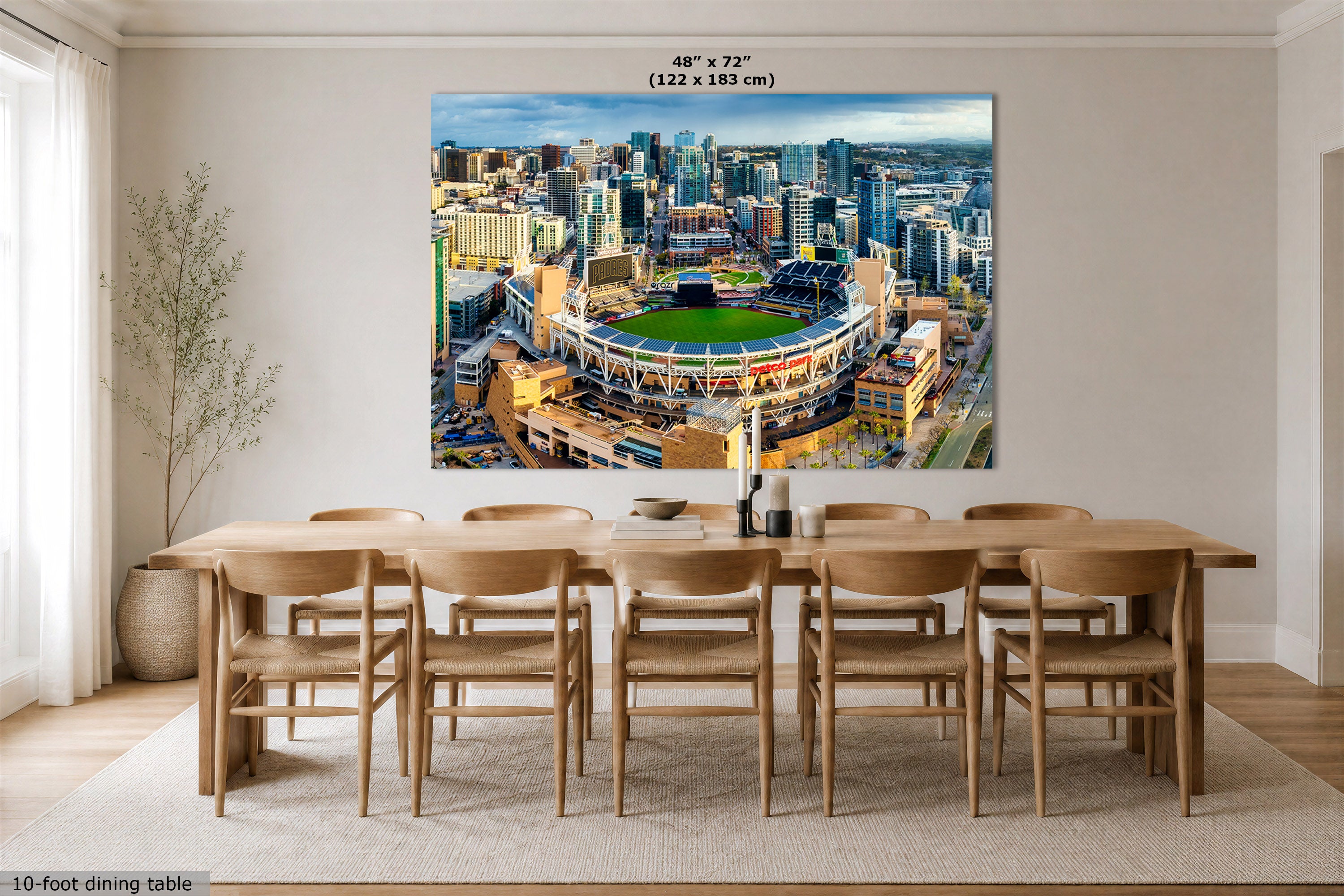 A San Diego Padres Stadium art print showing an aerial view of Petco Park and the San Diego, California city skyline, displayed above a wooden dining table in a modern dining room. The print includes size text at the top reading 48" x 72" (122 x 183 cm).